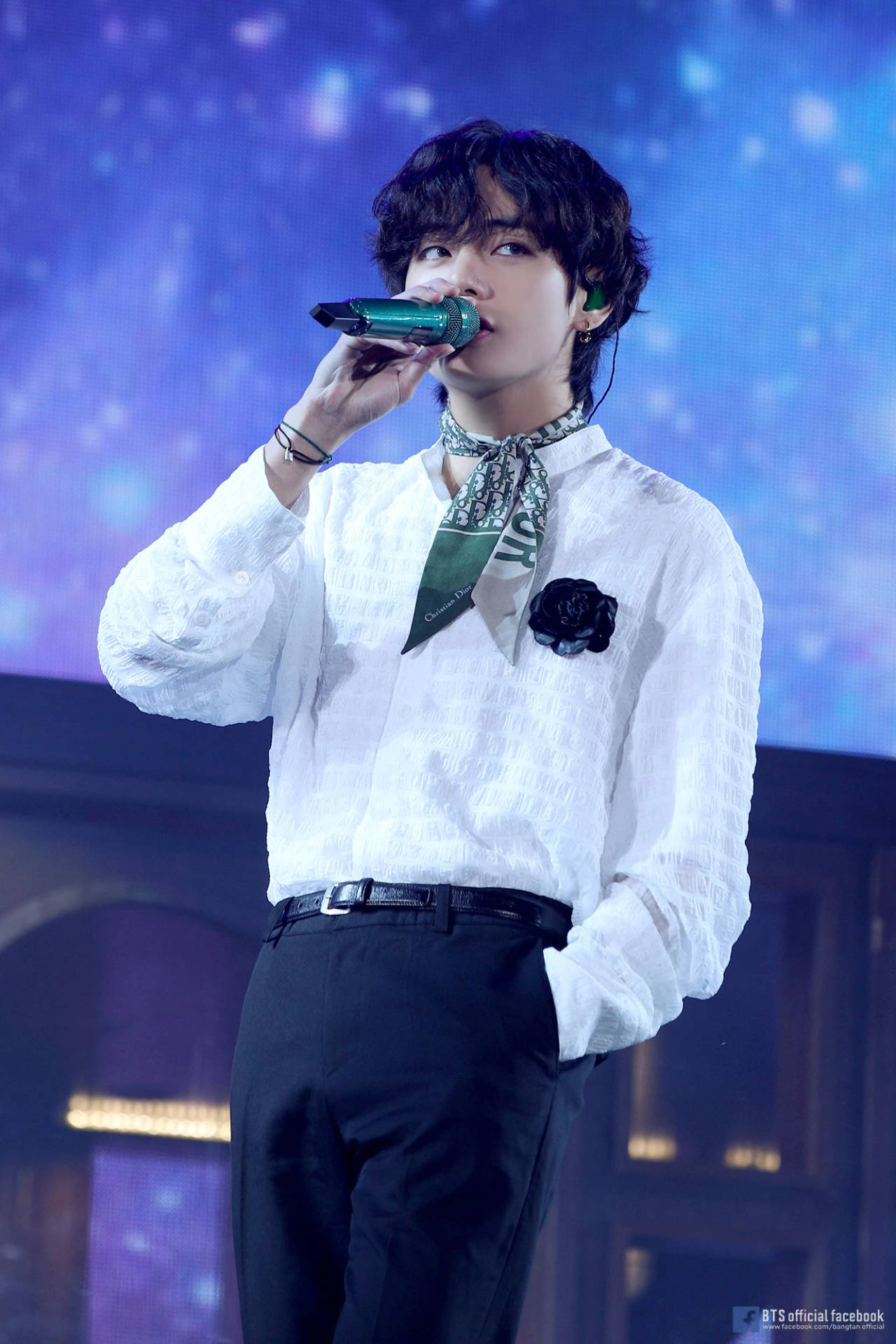 K-pop 歌手在藍色燈光下手持麥克風在舞台上表演。 — K Pop 壁紙