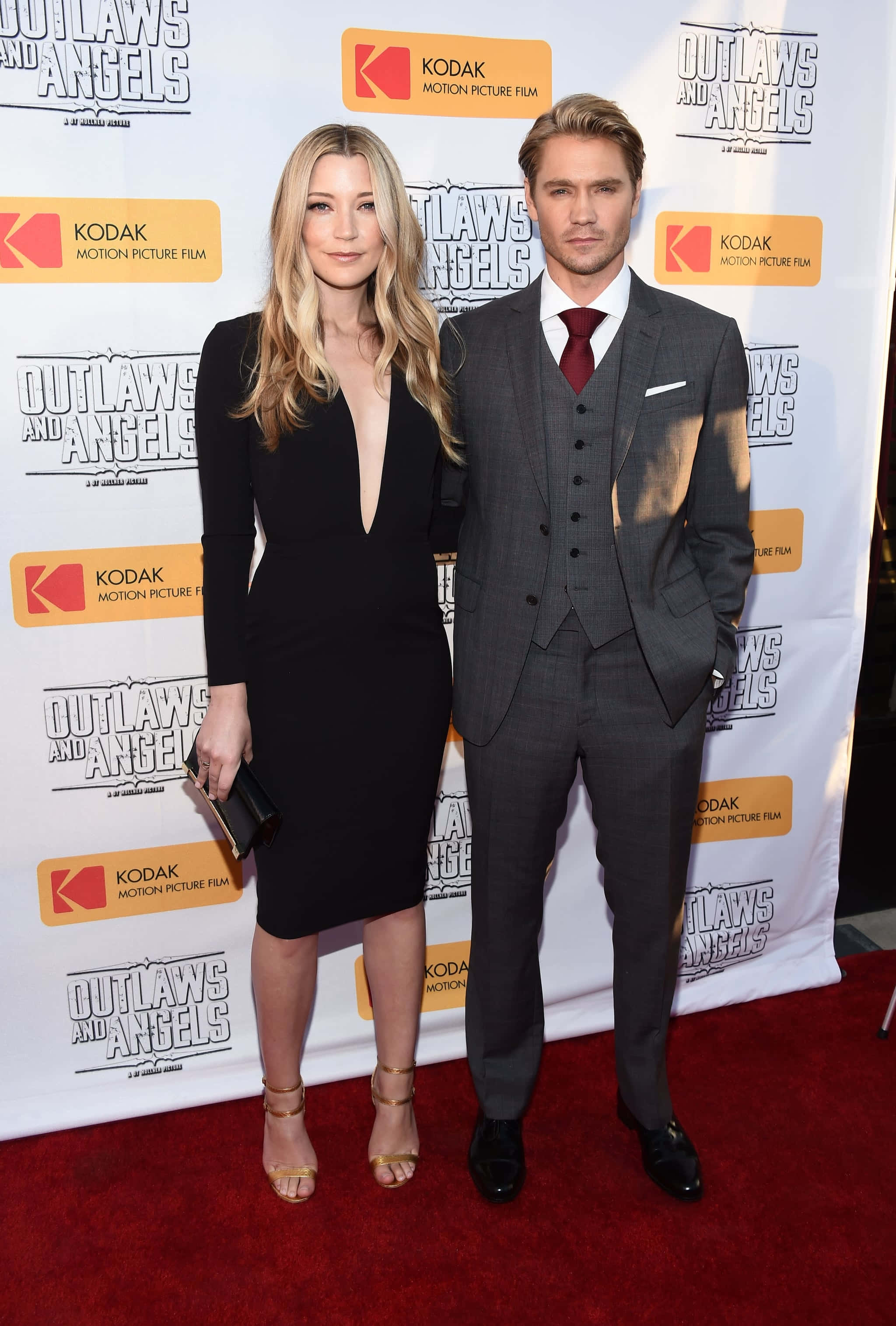 Sarah Roemer 桌布 壁紙 — 一男一女在電影首映會的紅地毯上自信地擺姿勢，背景帶有品牌標誌。