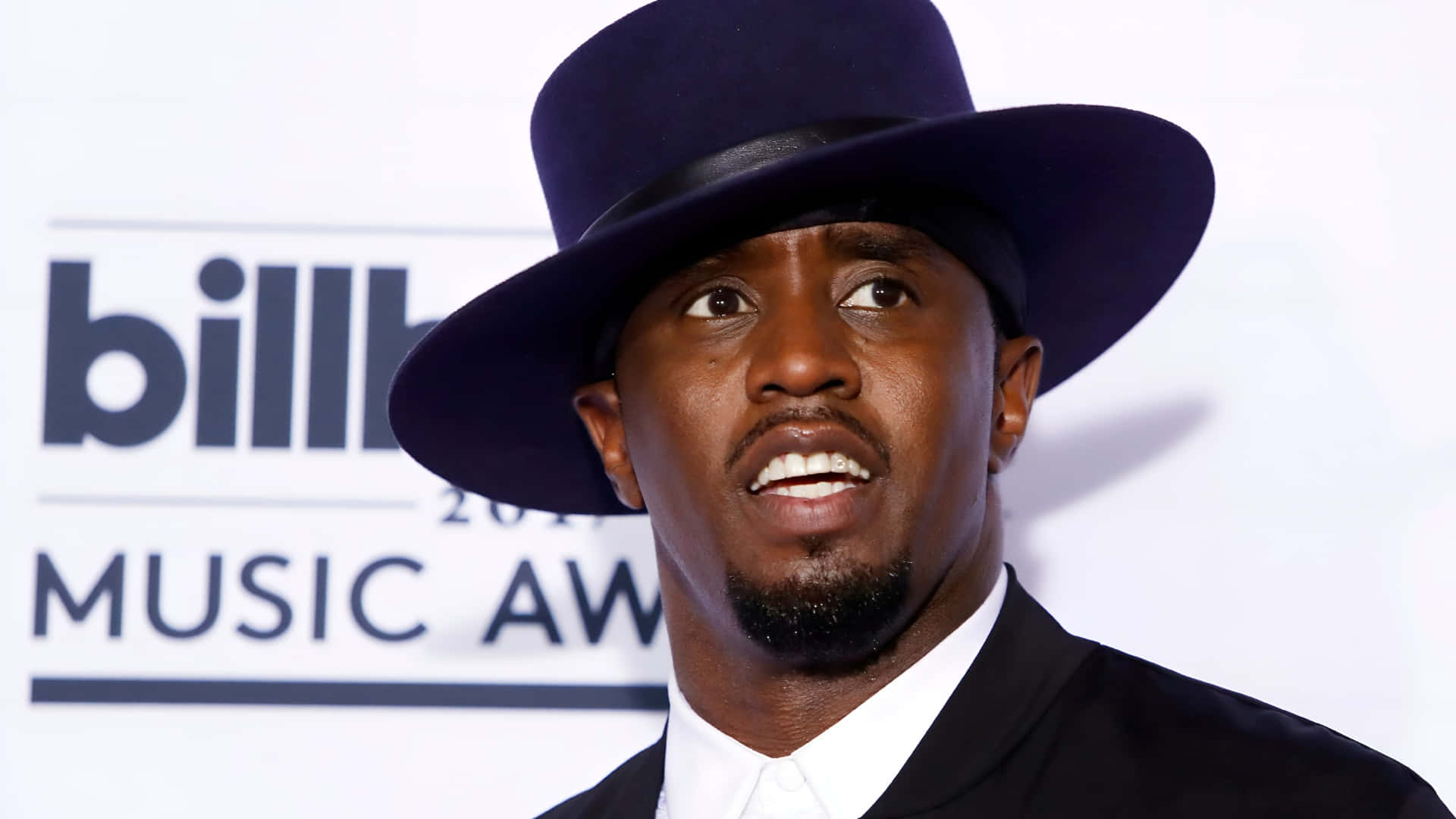  壁紙 — 一個戴黑色高帽、穿西裝的男人仰望Billboard音樂獎的背景。
