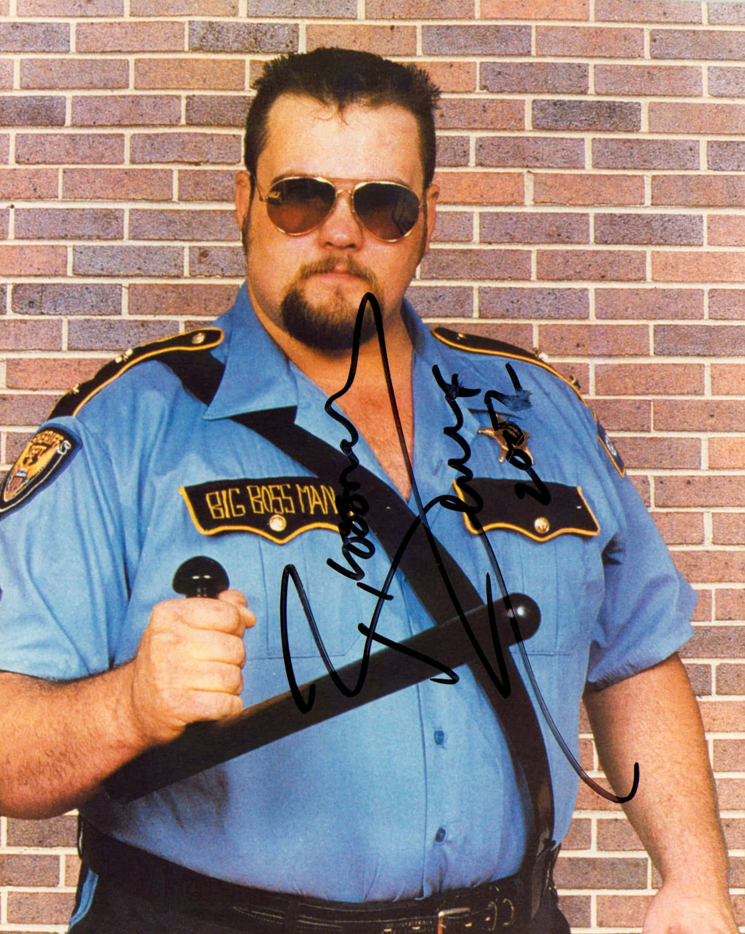  壁紙 — 一名身穿藍色警察制服、帶有「BIG BOSS MAN」徽章的男子，在磚牆背景下手持警棍。