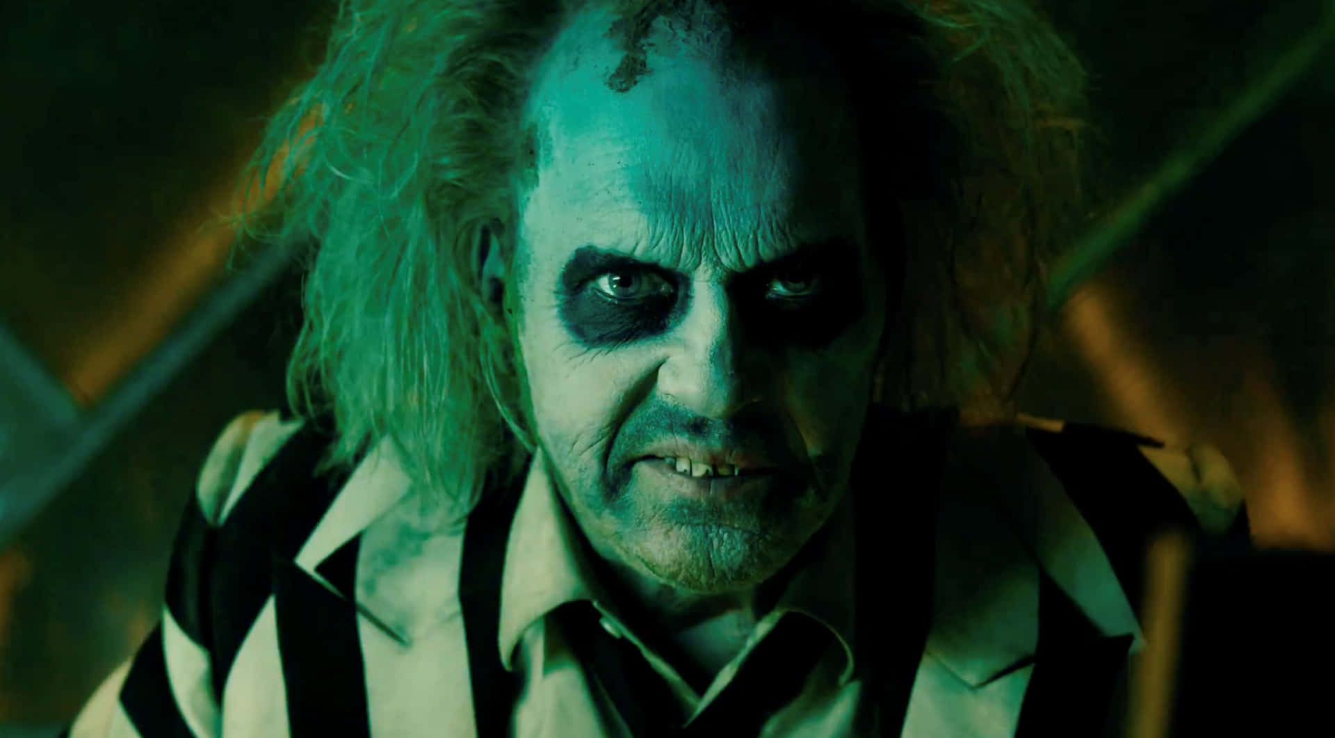  壁紙 — 一張令人畏懼的Beetlejuice特寫，擁有狂野的綠色頭髮和黑色眼妝，在詭異的綠色燈光下。