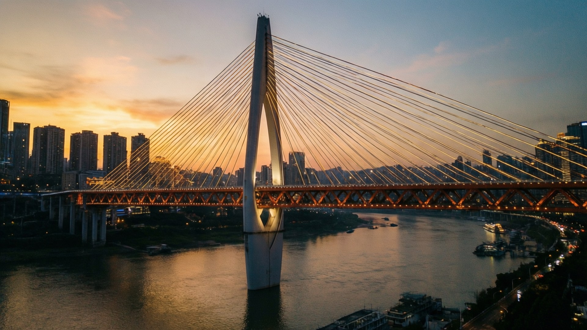 Bridge at Golden Hour 壁紙 — 一座現代斜張橋在日落時分在河上發出溫暖的光芒，背景是城市摩天大樓。