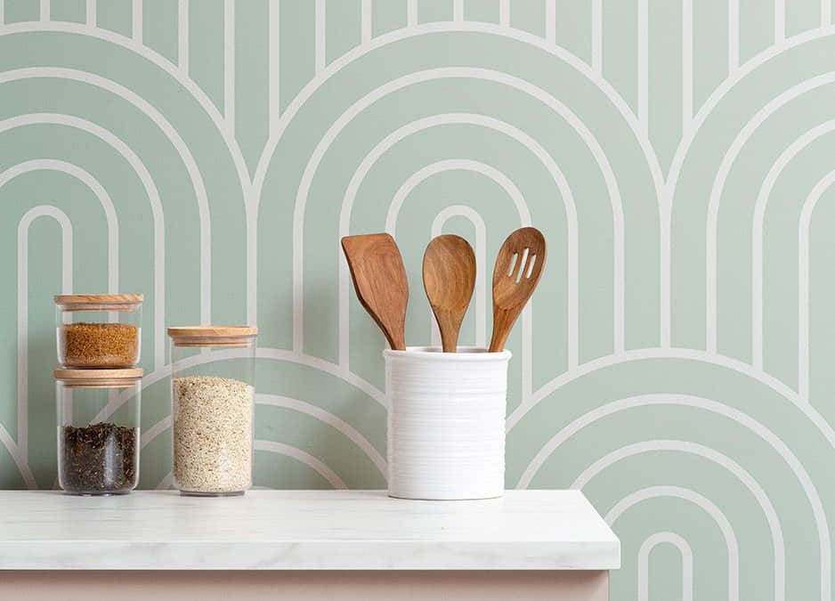  壁紙 — 現代廚房檯面，擺放木製廚具和玻璃罐，背景是薄荷綠色幾何圖案壁紙。
