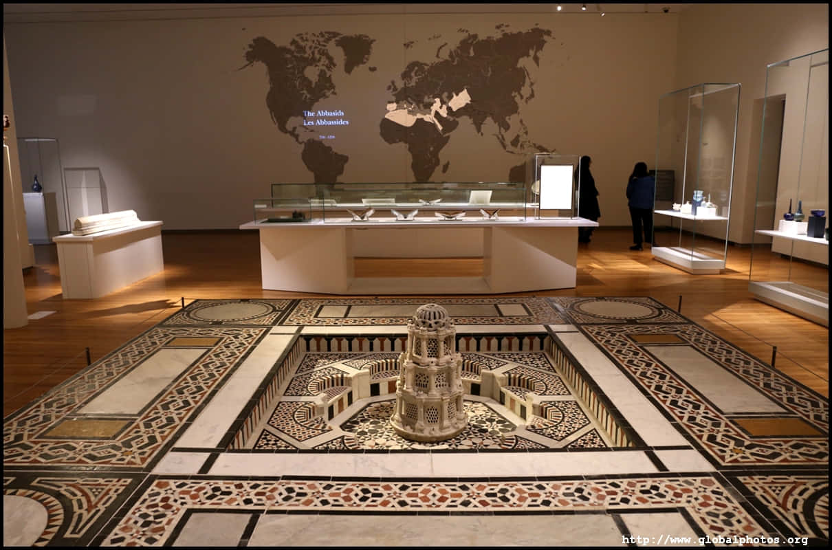Aga Khan Museum 桌布 壁紙 — 博物館畫廊展示了一個詳細的建築模型，位於華麗的馬賽克地板中央，牆上掛著世界地圖，背後是玻璃展示櫃。