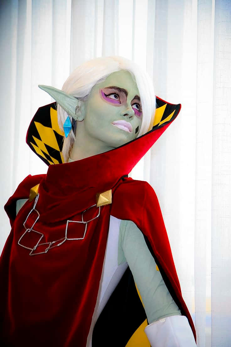  壁紙 — 一個穿著精緻綠色皮膚精靈cosplay、白髮和紅色斗篷的人站在純白色窗簾前。