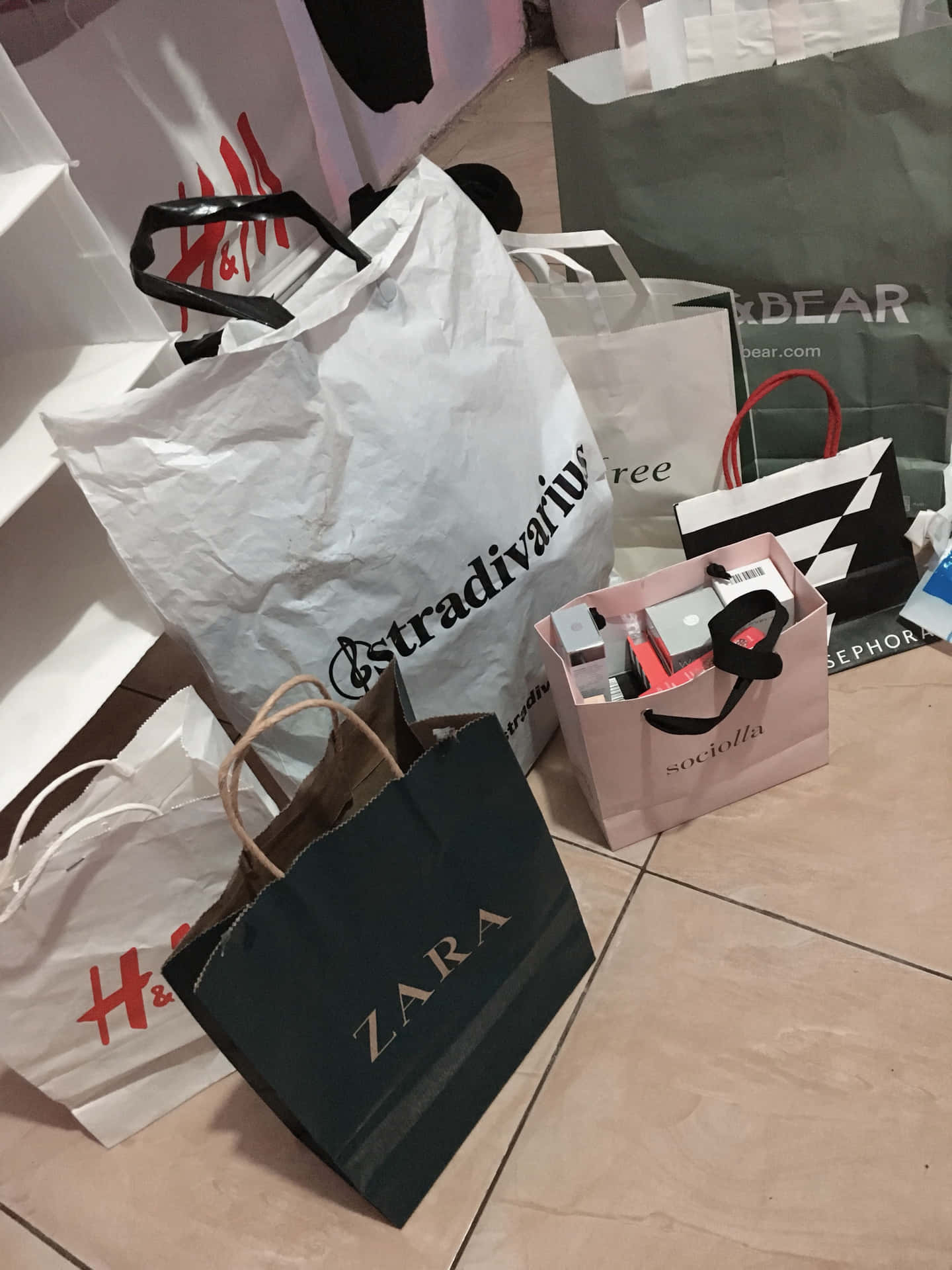  壁紙 — 一堆來自 H&M Zara 和 Sephora 的購物袋放在磁磚地上，購物後留下的景象。