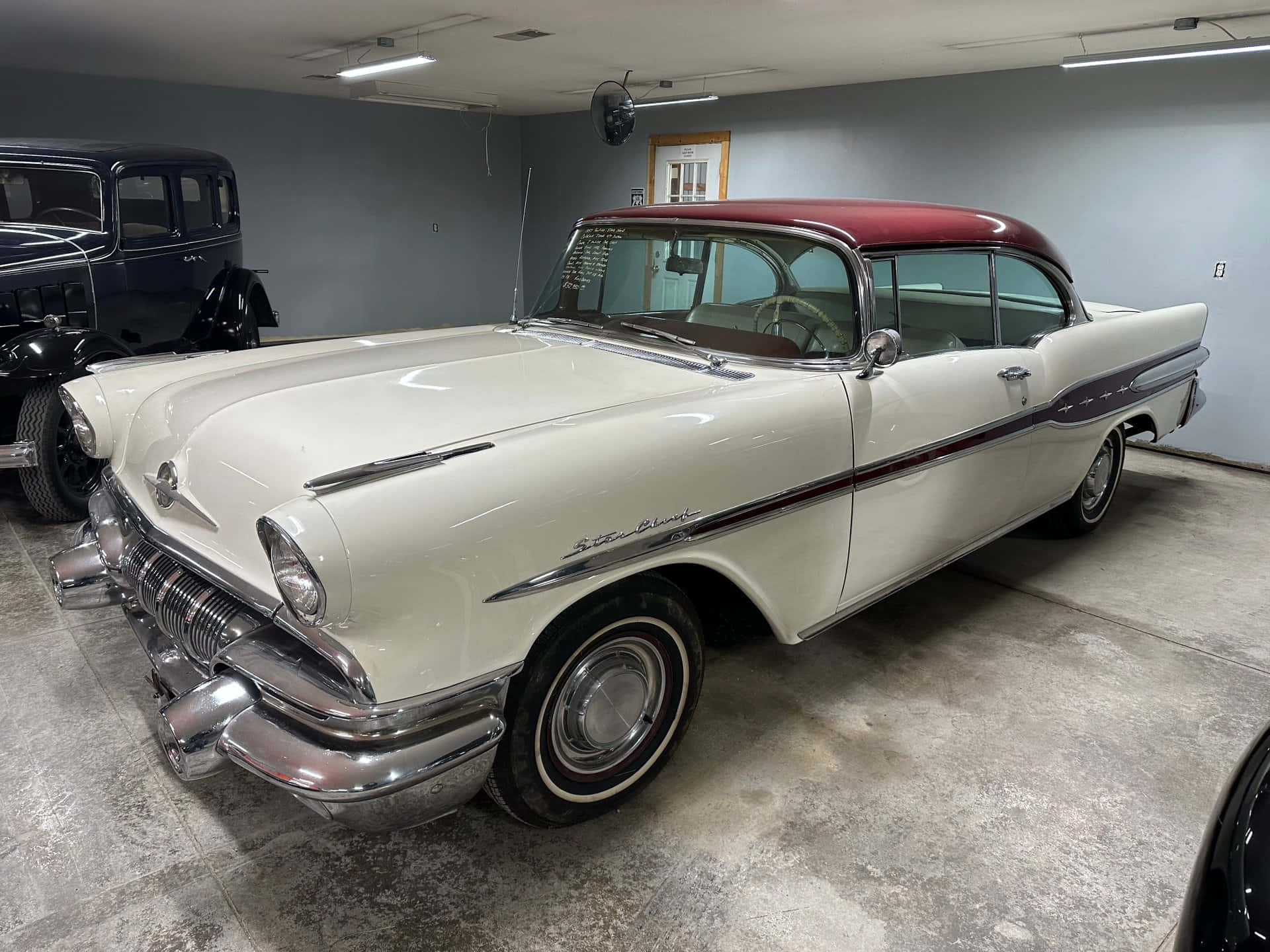Pontiac Star Chief 桌布 壁紙 — 一輛完美的奶油色和栗色1950年代雪佛蘭，帶有鍍鉻裝飾，在乾淨車庫的螢光燈下閃閃發光。