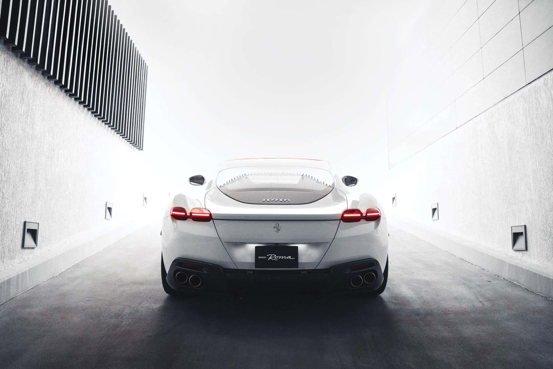 Ferrari Roma 桌布 壁紙 — 一輛純白色的法拉利 Roma 從後方閃耀，位於簡約混凝土隧道中央，光線鮮明。