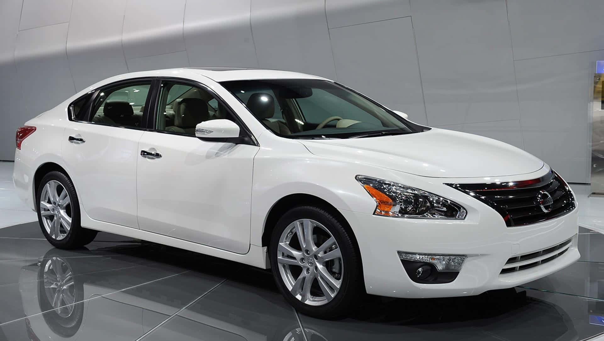 Nissan Altima 桌布 壁紙 — 一輛純白色的日產轎車在明亮的燈光下，於反射的展廳地板上閃閃發光。