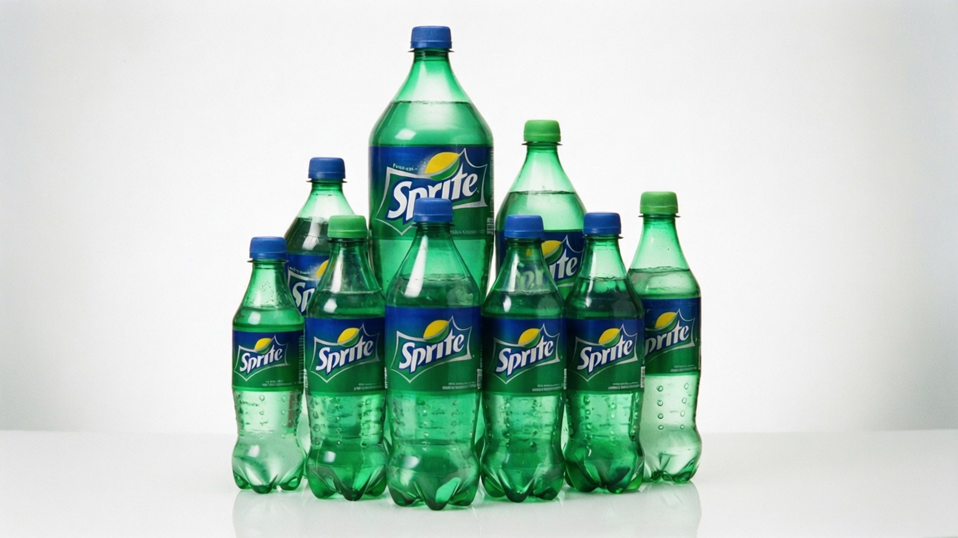 sprite 桌布 壁紙 — 一個由綠色雪碧瓶（藍色瓶蓋）組成的金字塔排列，置於白色表面上，背景為純白色。