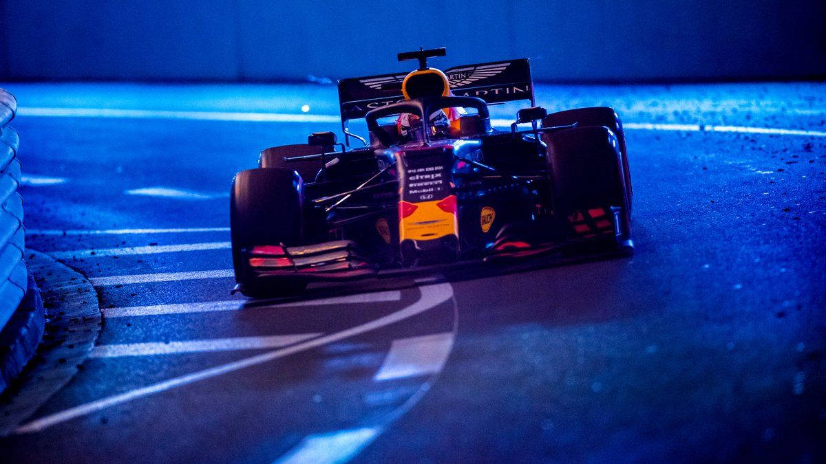 紅牛F1賽車在夜間於藍色賽道上比賽，帶有白色路緣。 — 賽車 壁紙