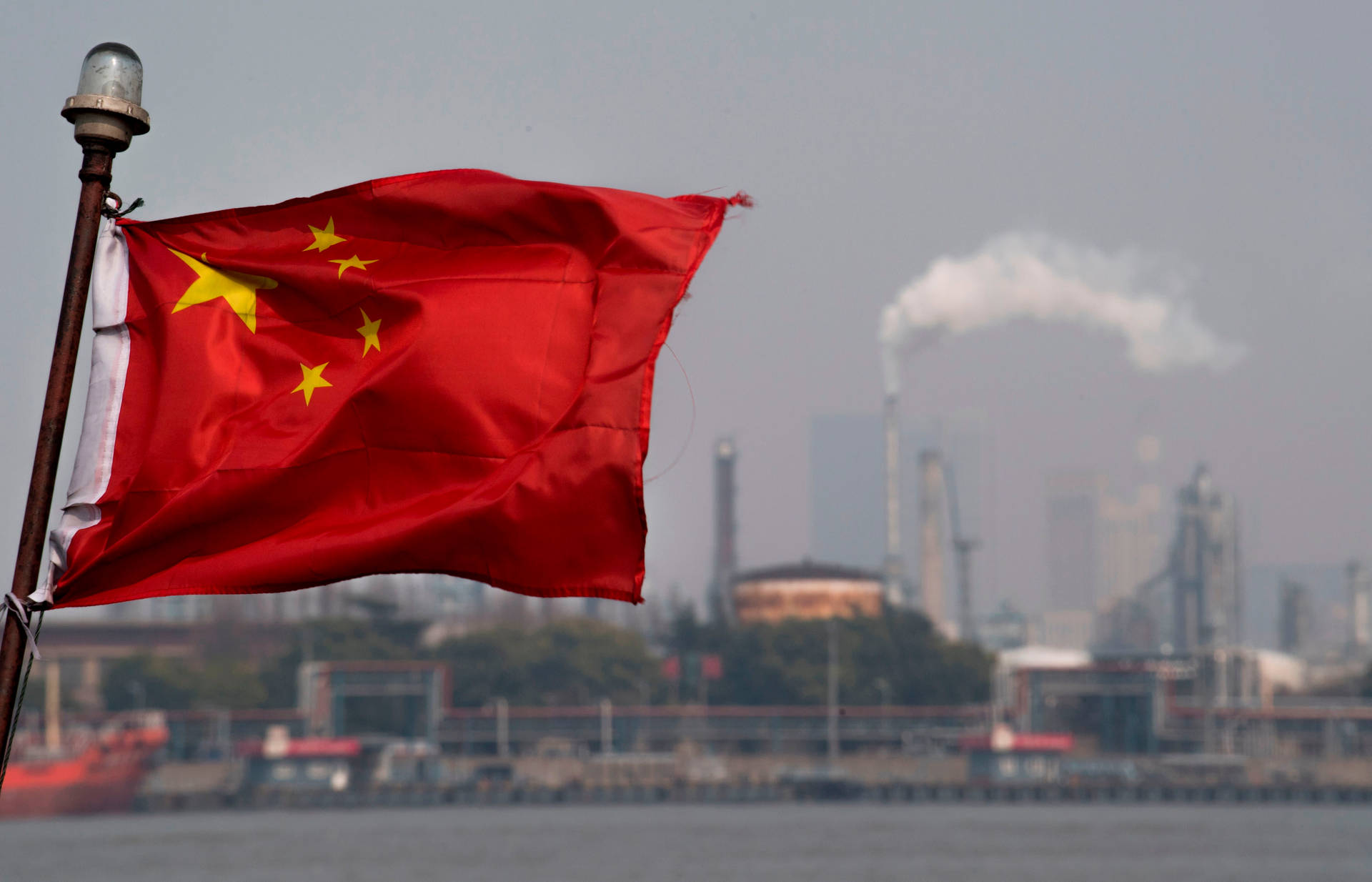 中國國旗在水邊飄揚，背景有工業煙囪。 — 中國國旗 壁紙