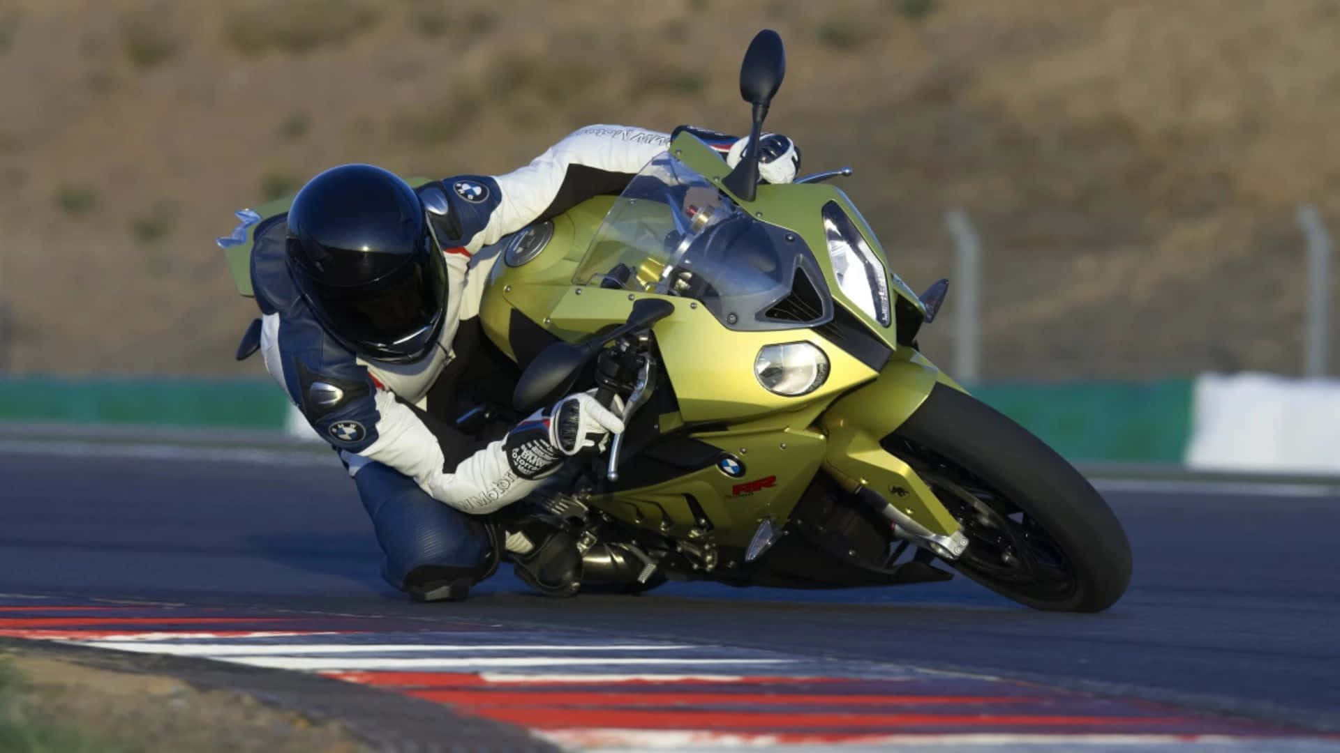  壁紙 — 一名全副裝備的騎士在賽道上騎著鮮綠色運動機車，急劇傾斜入彎。