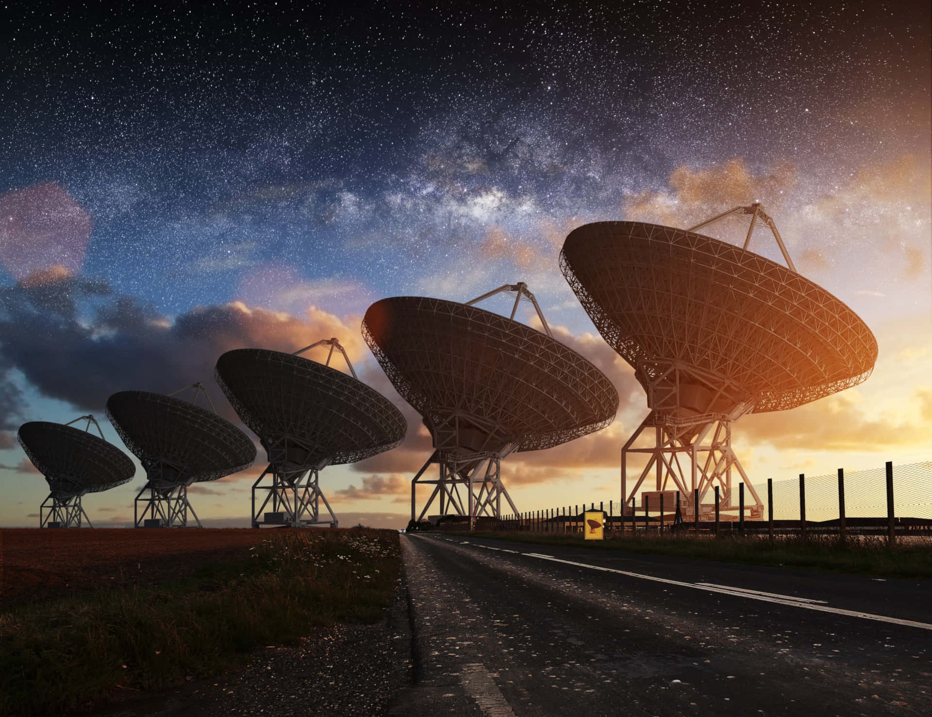  壁紙 — 一排巨大的無線電望遠鏡在星光燦爛的暮色天空襯托下呈現剪影，銀河在上方閃耀。