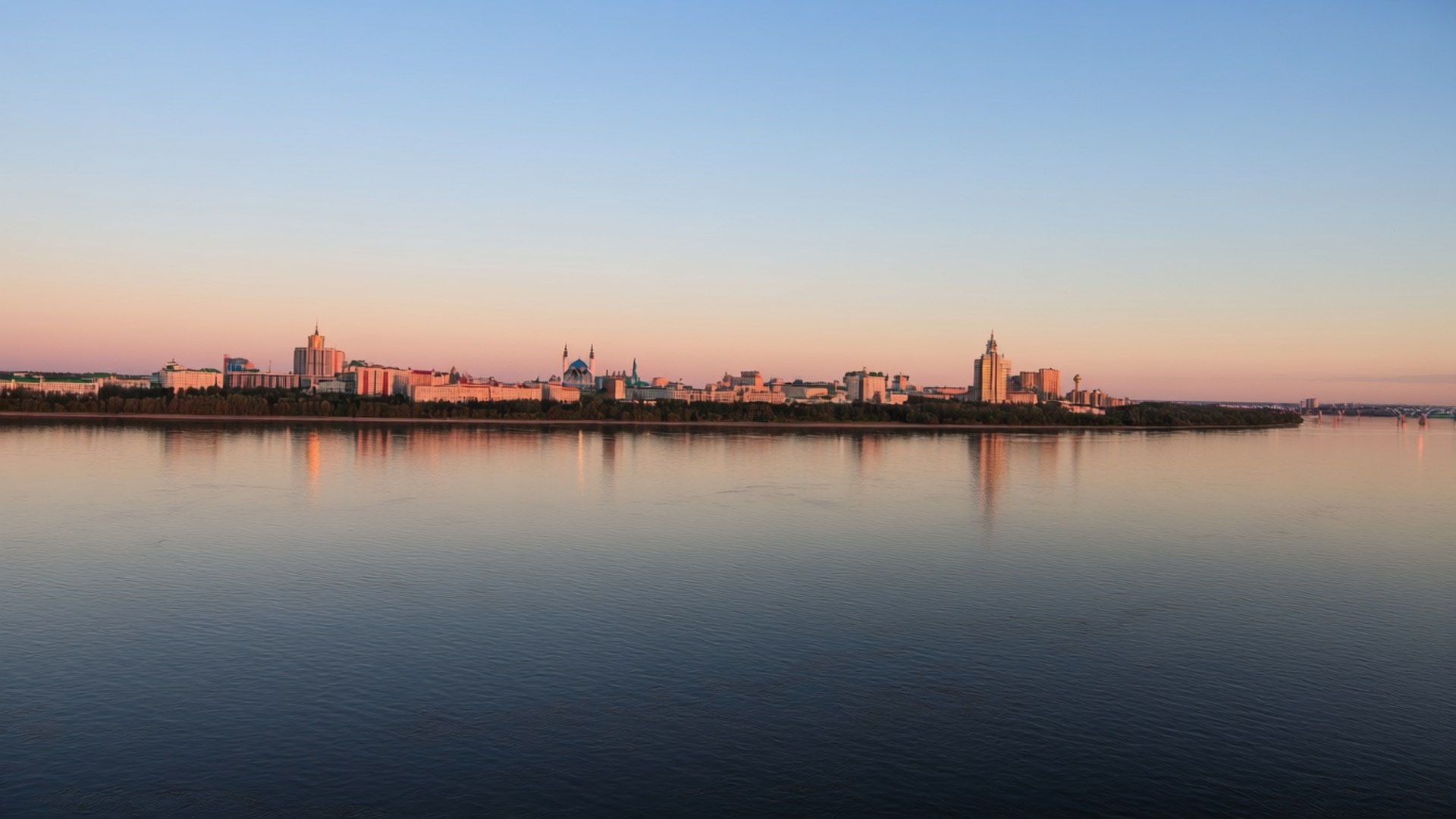 Kazan Cityscape Sunset 壁紙 — 黃昏時分，寧靜的城市天際線在漸變天空下柔和地倒映在平靜的水面上。