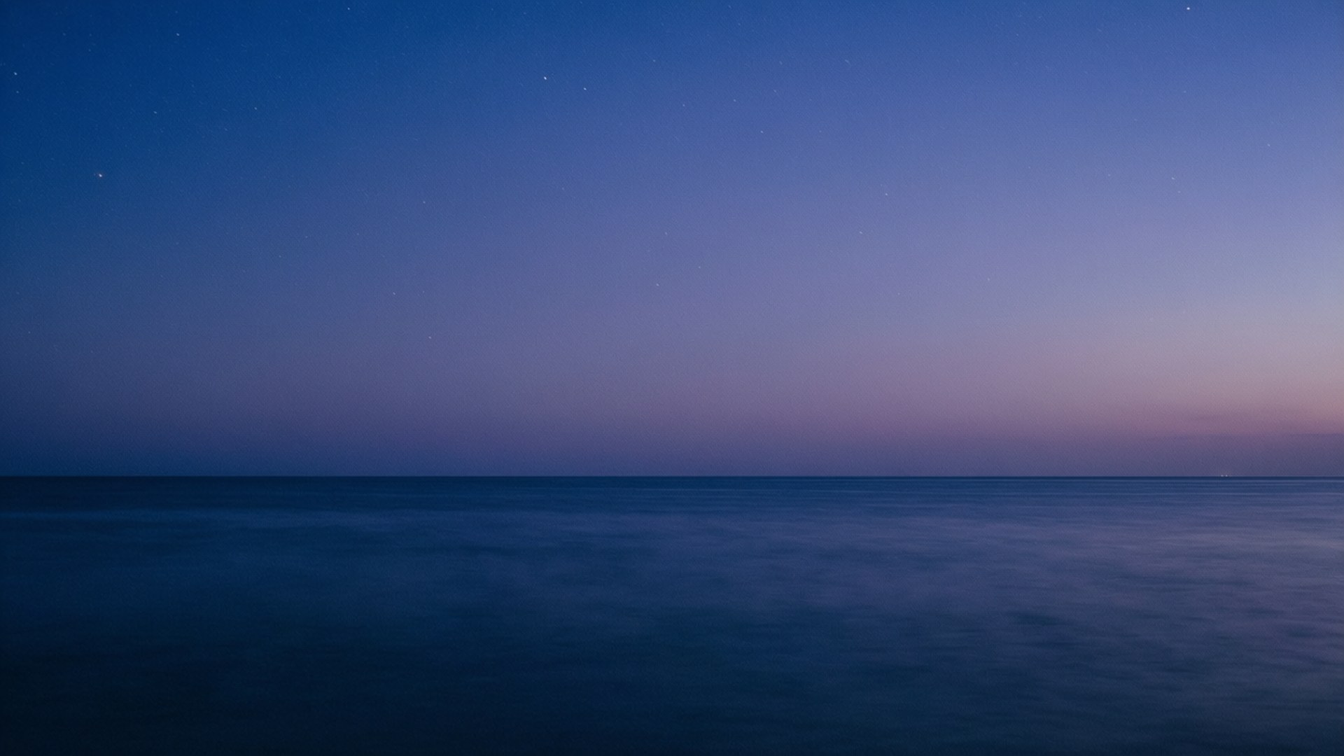 Twilight Ocean Horizon 壁紙 — 寧靜的黃昏海景，深藍色星空在平靜的海平線附近逐漸褪成紫色。