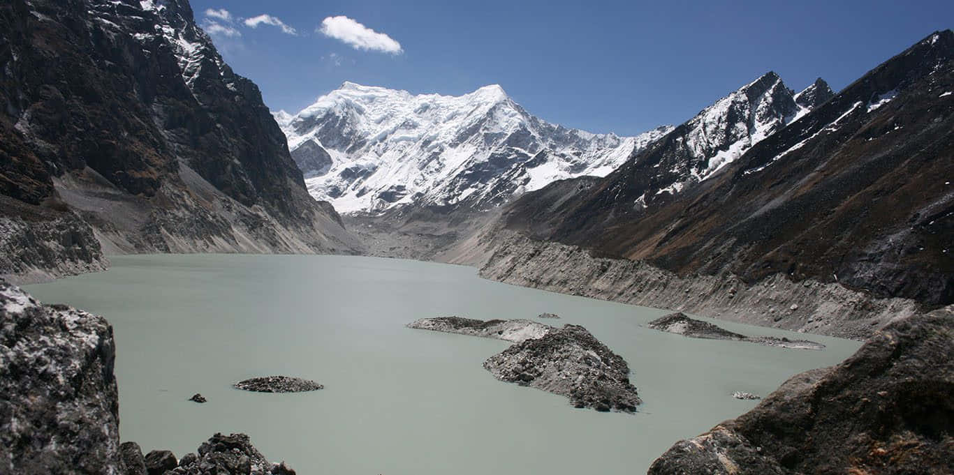  壁紙 — 一個寧靜的冰川湖，坐落在崎嶇的雪山之間，天空湛藍清澈。
