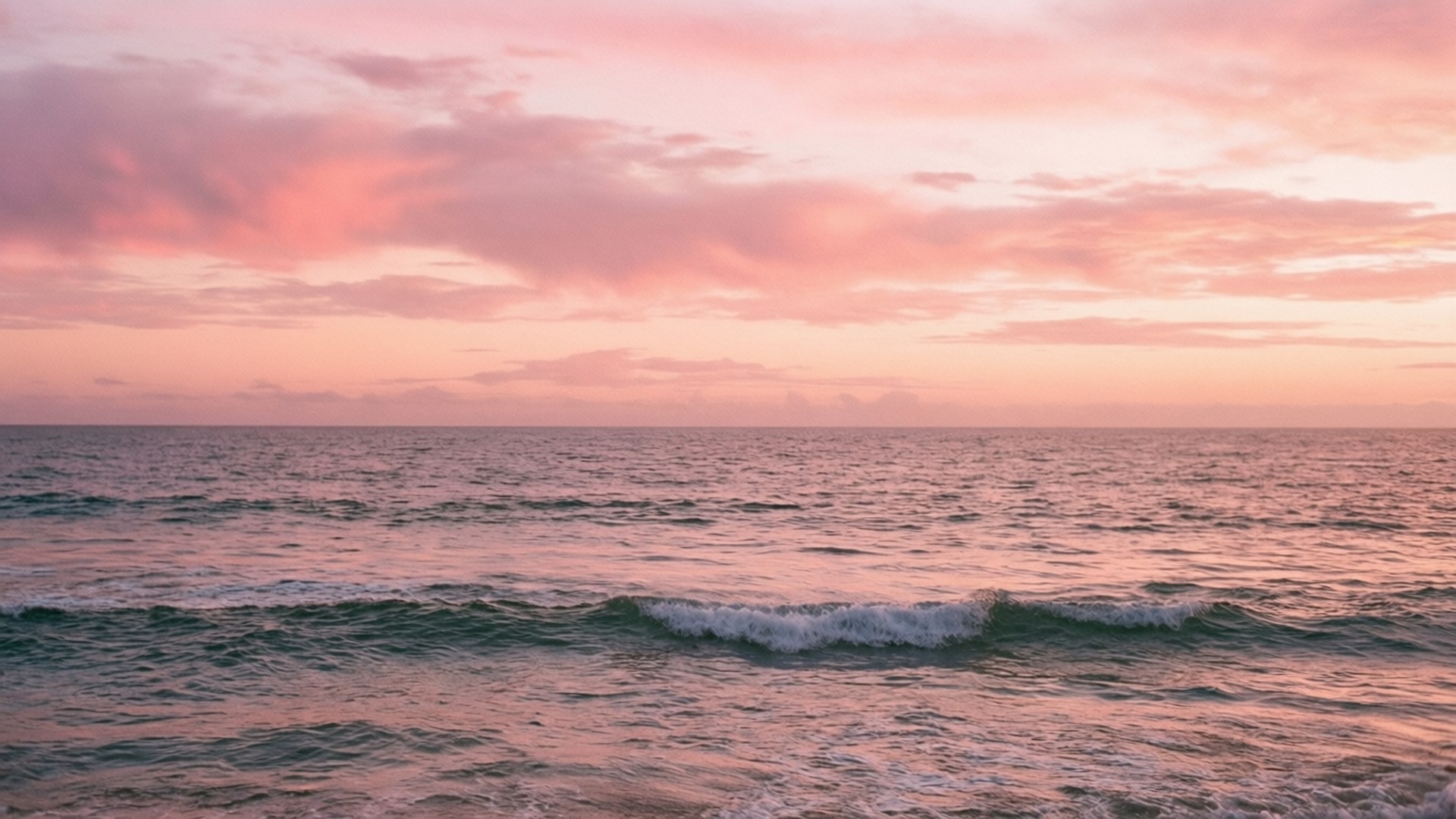 Pink Horizon 壁紙 — 日落時分寧靜的海洋，柔和的粉紅雲彩映照在輕柔的波浪上。