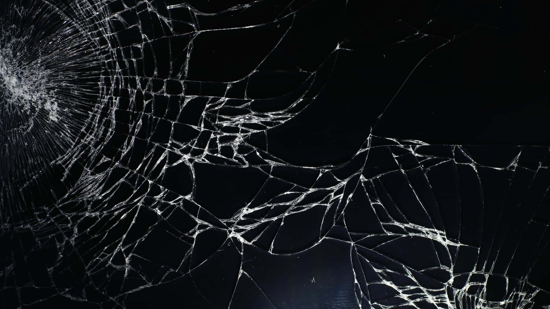  壁紙 — 在純黑色背景上，一塊破碎的玻璃表面帶有複雜的白色裂紋。