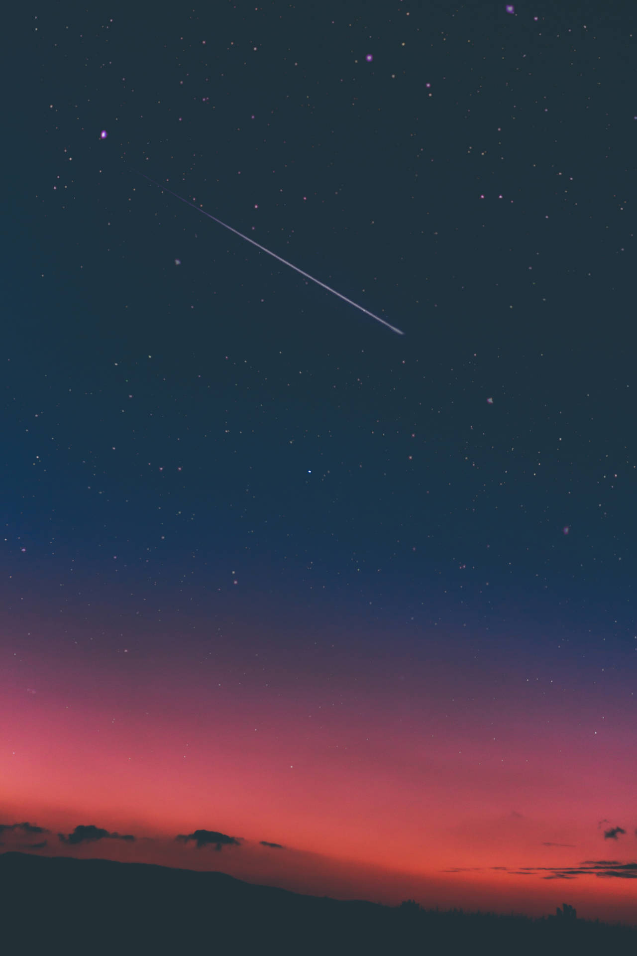 一顆流星越過暮色天空，背景是山巒的剪影。 — 太空 壁紙