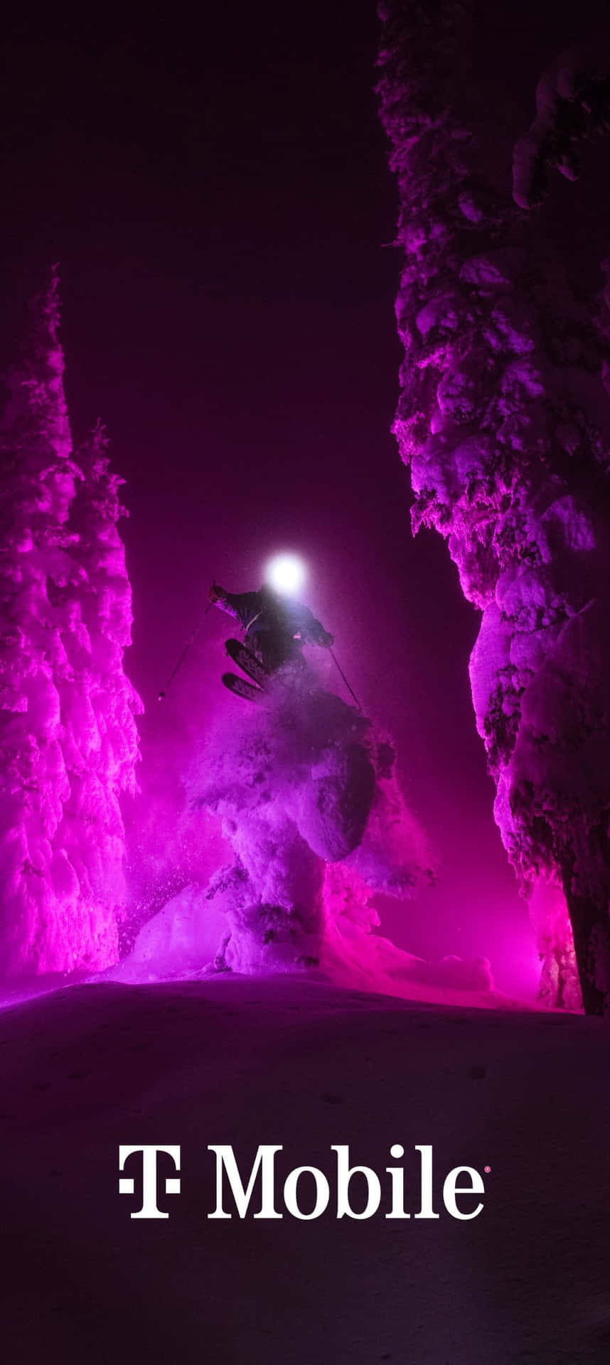  壁紙 — 一名滑雪者在夜間跳過積雪覆蓋的森林，被充滿活力的紫色燈光照亮，投射出戲劇性的陰影。