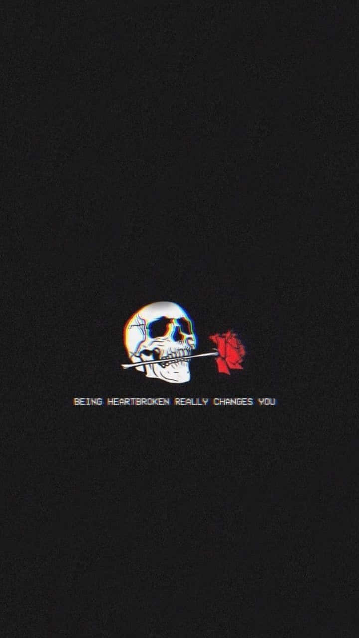  壁紙 — 一個骷髏頭嘴裡叼著一朵紅玫瑰，背景為黑色，下方有文字。