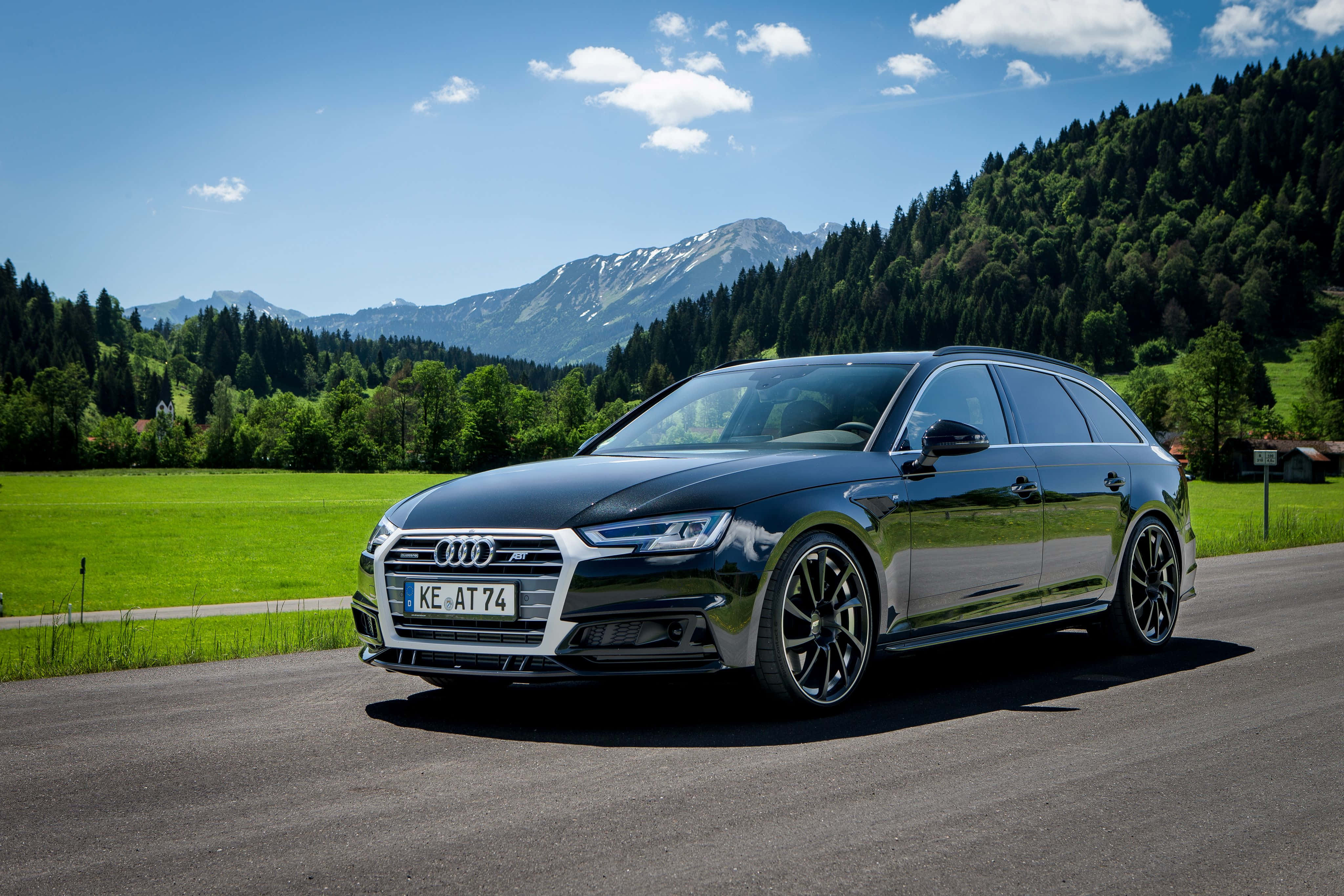 Audi A4 桌布 壁紙 — 一輛時尚的黑色奧迪旅行車在藍天白雲下的山路上閃閃發光。