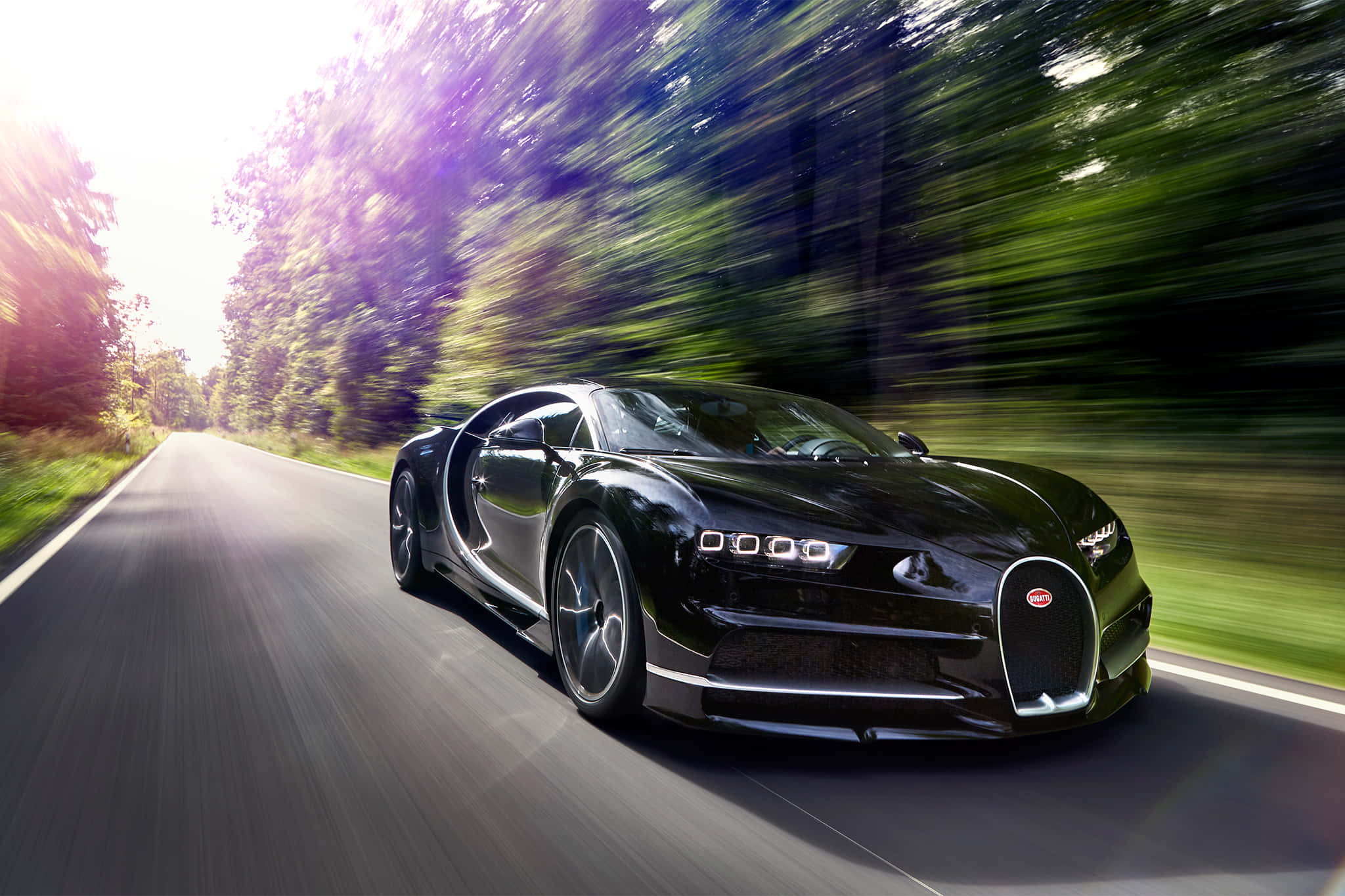 Bugatti Chiron 桌布 壁紙 — 一輛時尚的黑色Bugatti Chiron在陽光明媚的森林道路上疾馳，動態模糊強調了速度。
