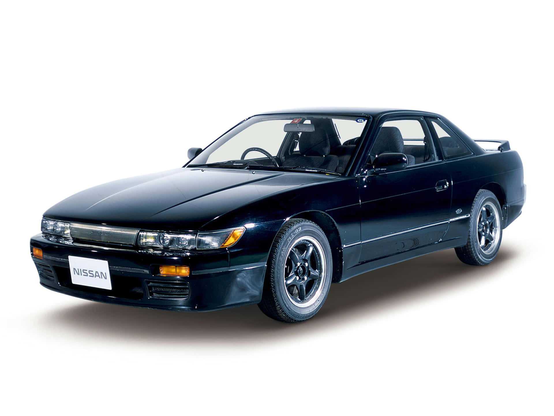  壁紙 — 一輛時尚的黑色日產運動轎跑車，配備銀色輪圈和光澤飾面，在攝影棚燈光下展示。