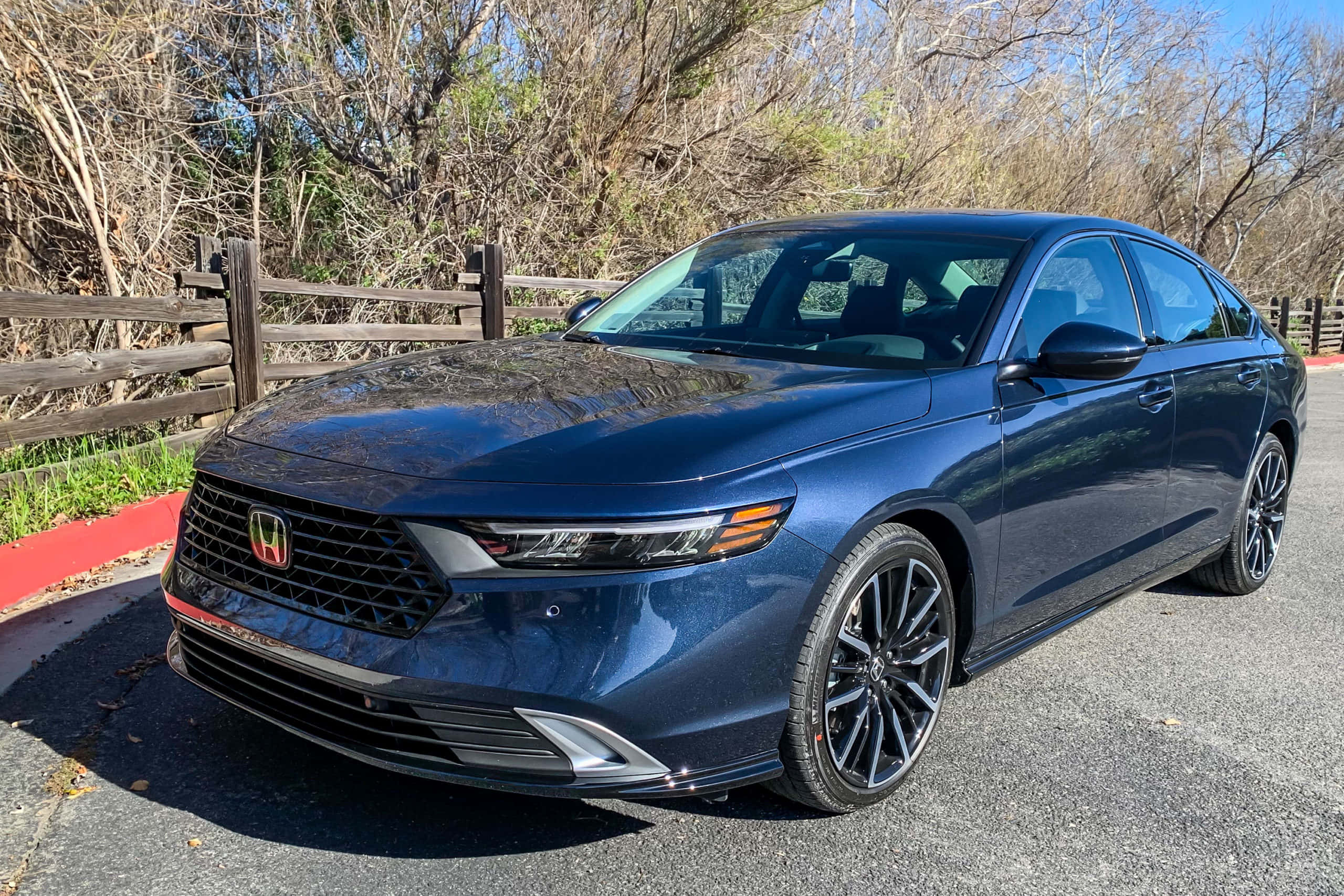 Honda Accord 桌布 壁紙 — 一輛時尚的藍色本田轎車停在柏油路上，旁邊是木柵欄和光禿禿的樹木，在明亮的日光下。
