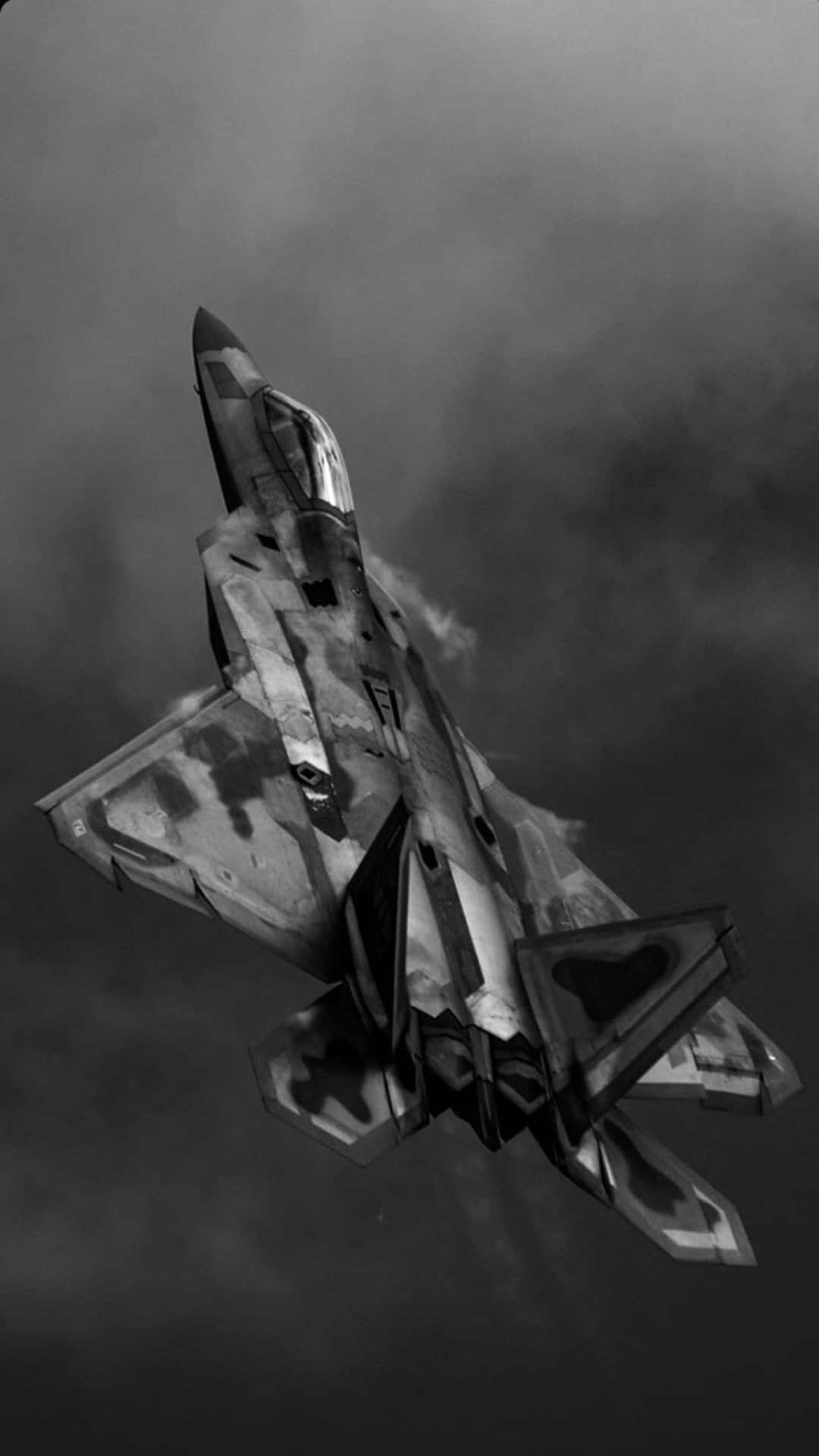  壁紙 — 一架流線型戰鬥機在戲劇性的黑白鏡頭中穿過濃密的灰色雲層翱翔。