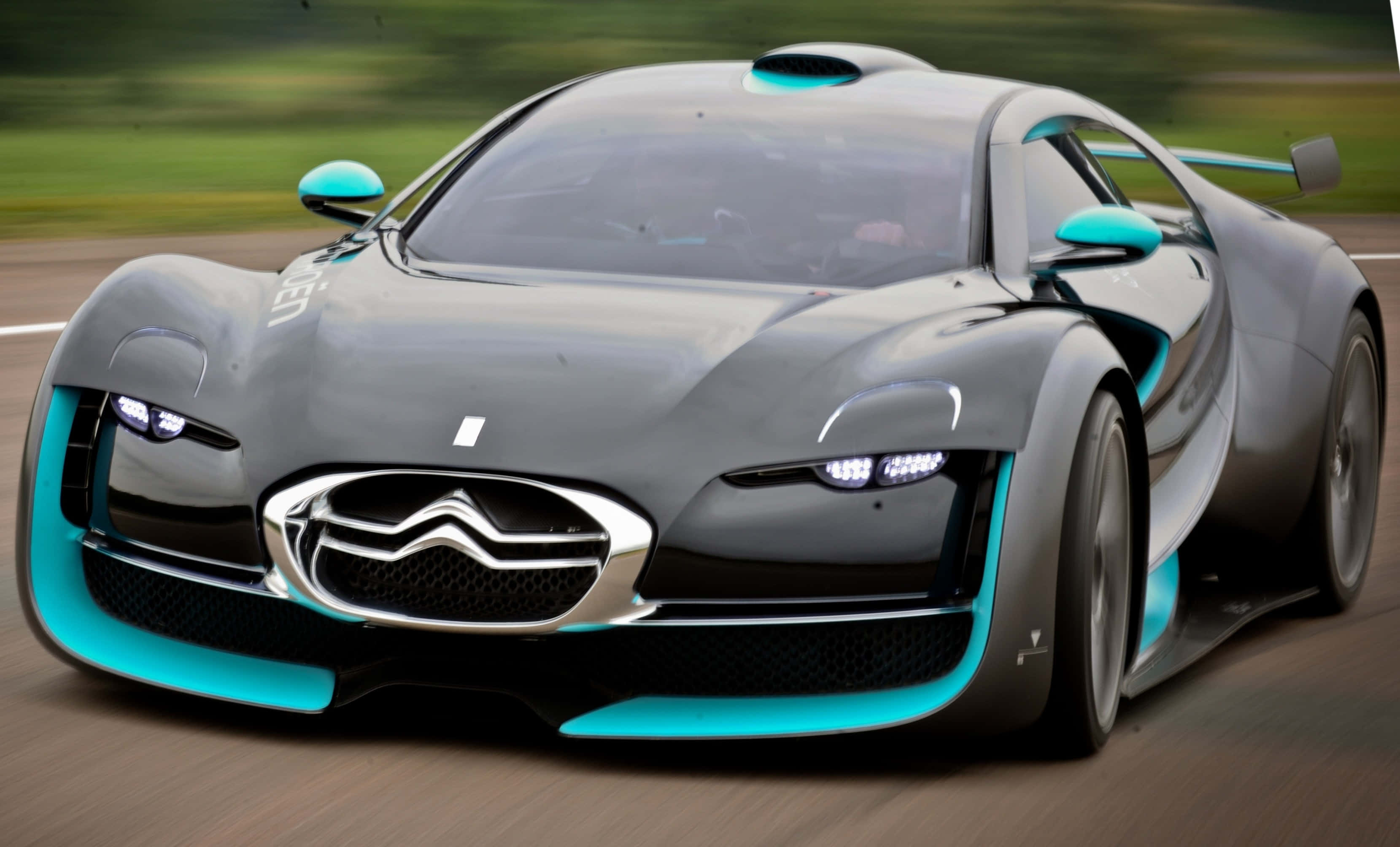 Citroen Ds Survolt 桌布 壁紙 — 一輛時尚的灰色雪鐵龍概念車，帶有綠松石色點綴，在模糊的賽道上疾馳。