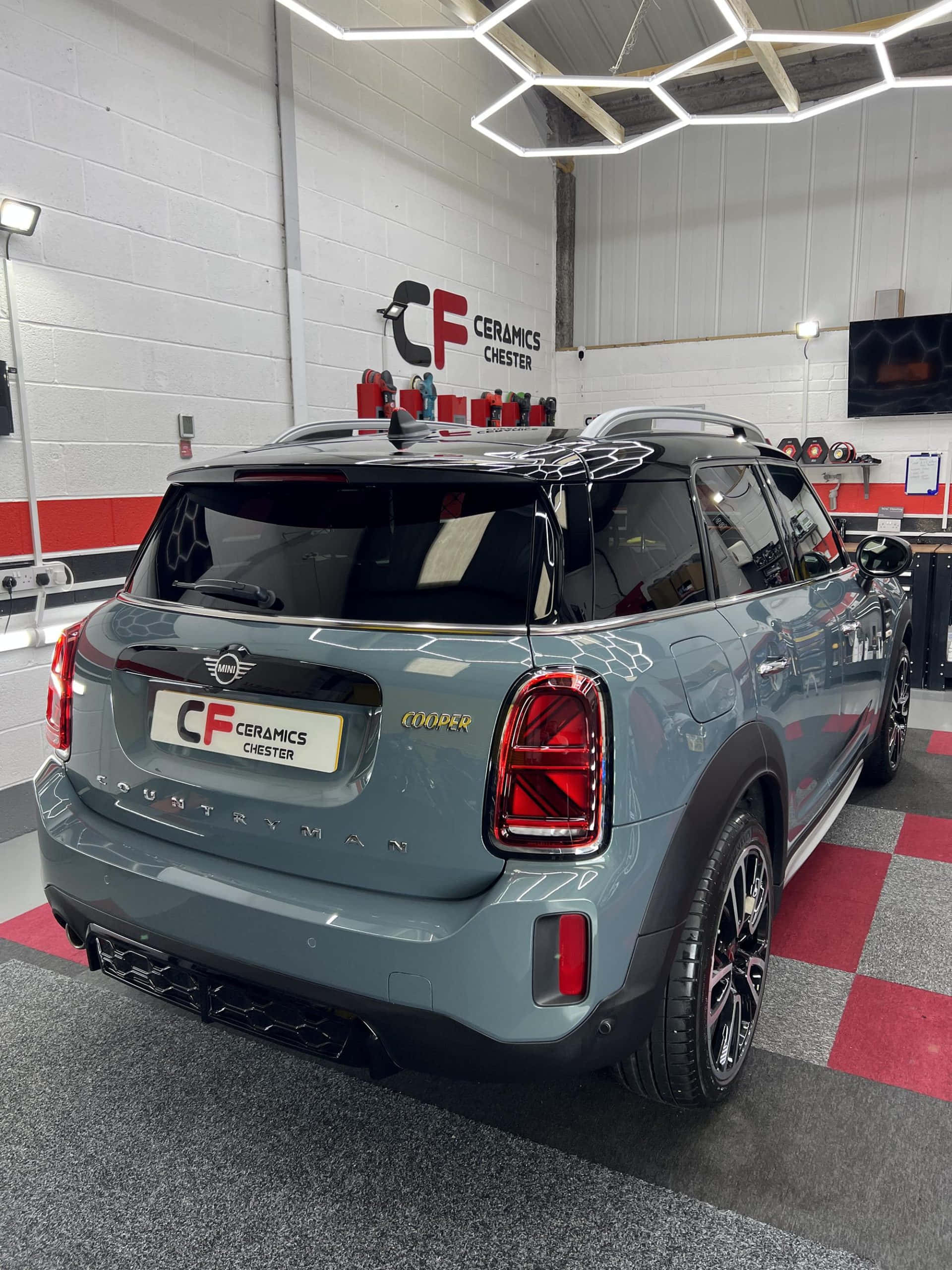 Mini Cooper Countryman 桌布 壁紙 — 一輛時尚的灰色MINI Countryman Cooper停放在室內，地面是紅灰格子地板，上方是現代六角形燈光。