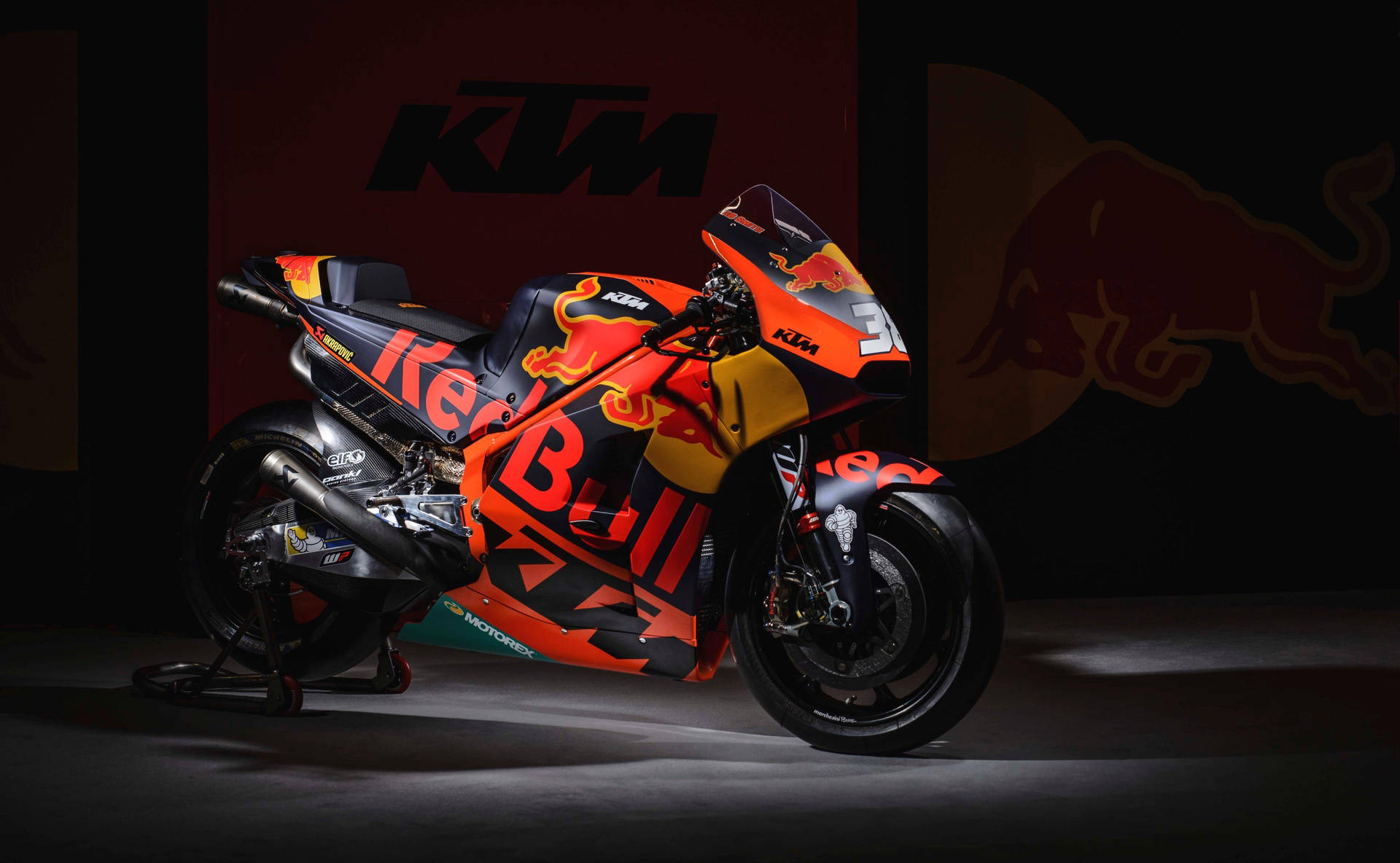 KTM Red Bull賽車摩托車在攝影棚中，帶有戲劇性照明和品牌背景。 — 4K 壁紙
