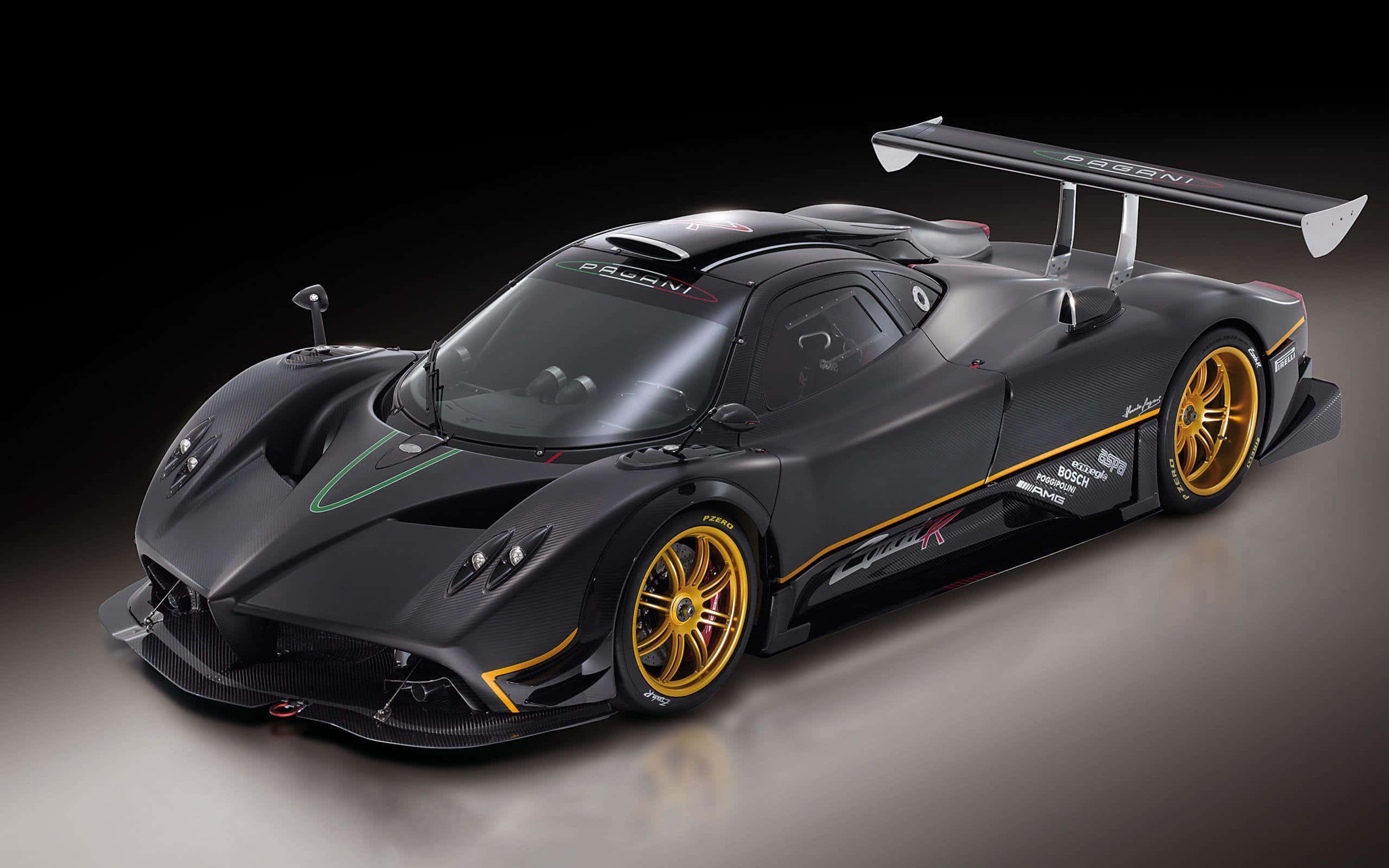 Pagani Zonda R 桌布 壁紙 — 一輛時尚的消光黑色帕加尼Zonda R賽車，配備金色輪圈和空氣動力學尾翼，在攝影棚燈光下閃耀。