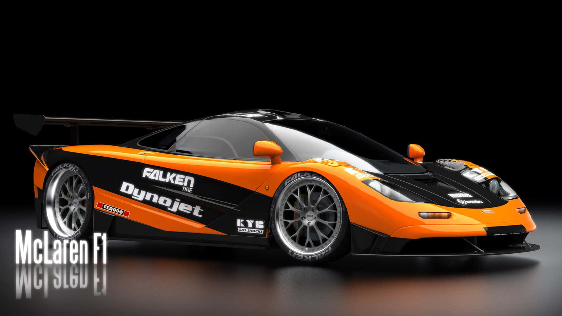 Mclaren F1 桌布 壁紙 — 一輛帶有贊助商貼紙的時尚橙色和黑色McLaren F1跑車在帶有反射地板的黑暗工作室中展示。