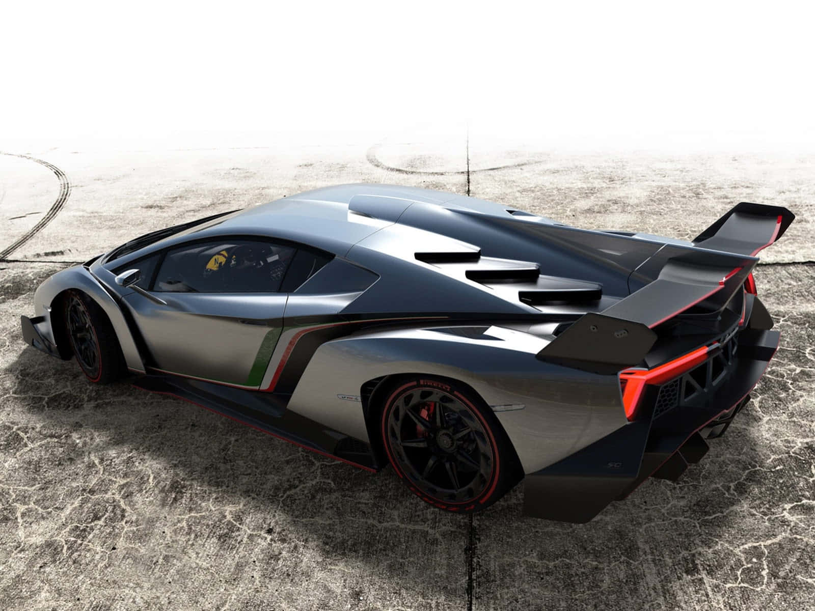 Lamborghini Veneno 桌布 壁紙 — 一台流線型銀色藍寶堅尼Veneno帶有紅色點綴，停放在裂開的混凝土上，展示其進取的氣動力設計及大型尾翼。