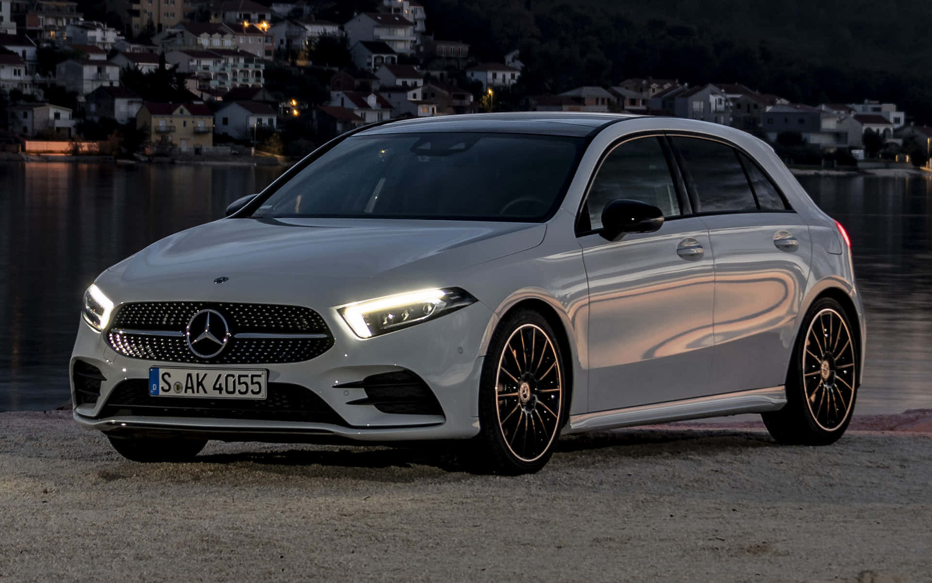 Mercedes Benz A-class 桌布 壁紙 — 一輛時尚的銀色 Mercedes-Benz A-Class 在黃昏時停泊在海濱，背景是亮燈的房屋。