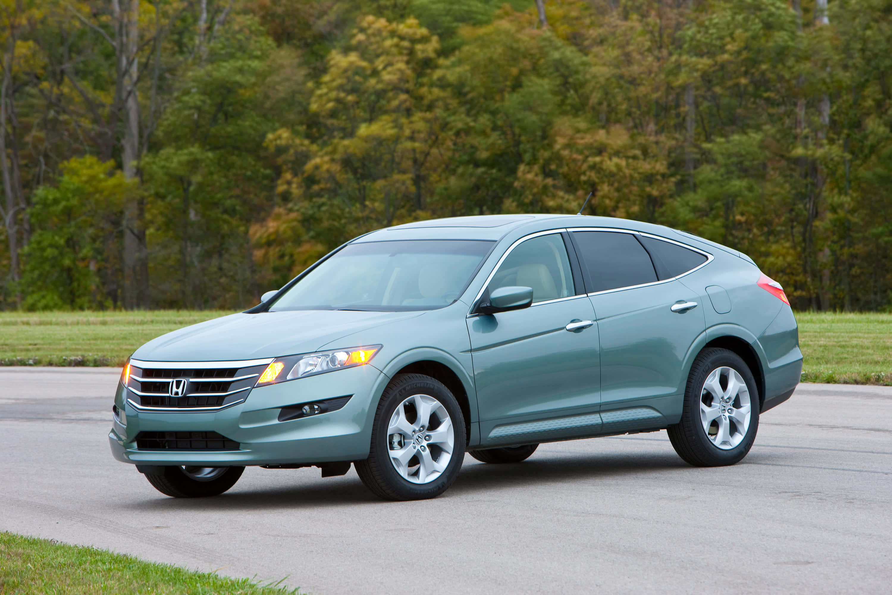 Honda Crosstour 桌布 壁紙 — 一輛時尚的青色本田 Crosstour SUV 停在鋪砌的道路上，背景有秋天的樹木。