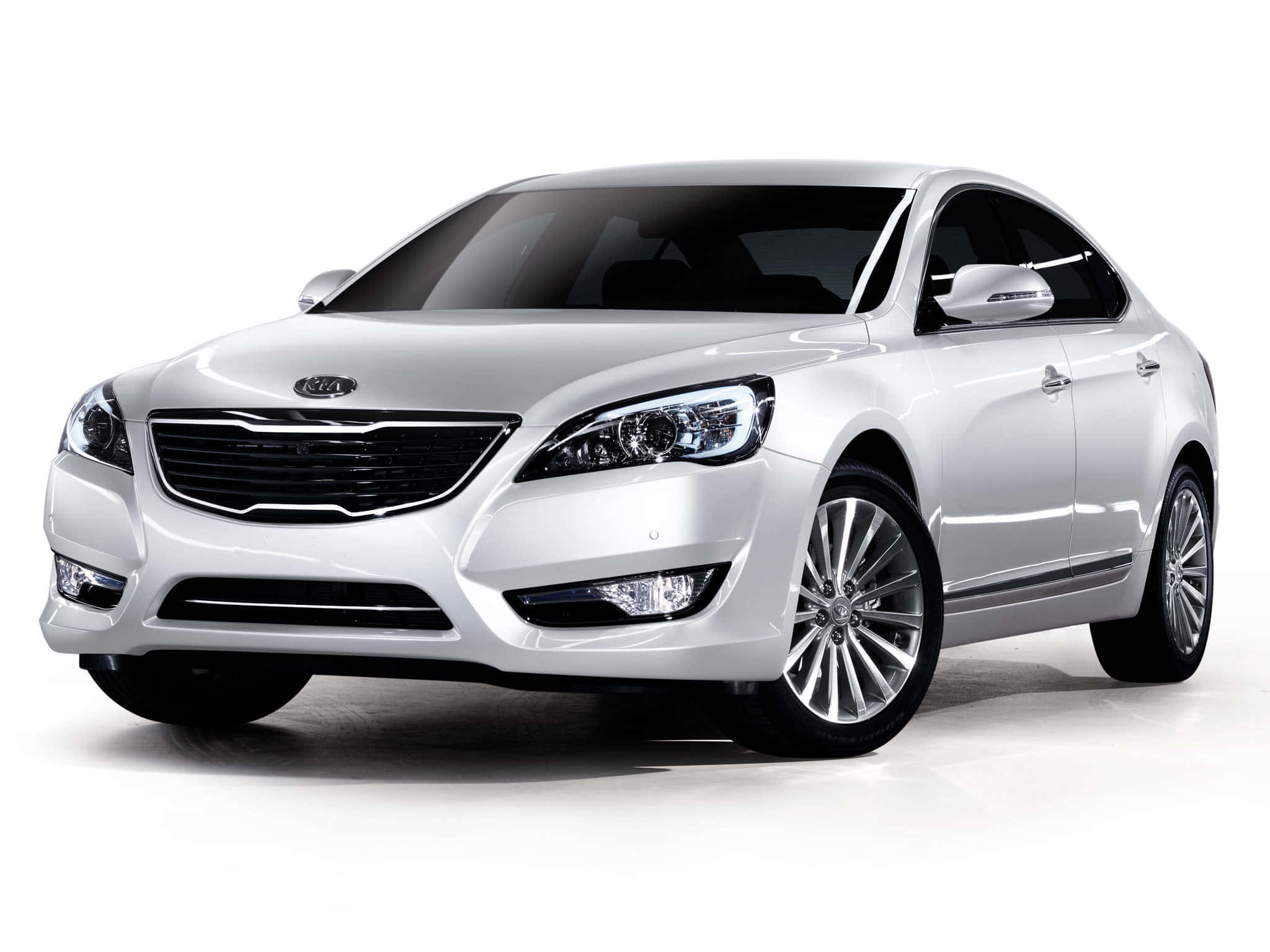 Kia Cadenza 桌布 壁紙 — 一輛時尚的白色起亞轎車在攝影棚燈光下閃耀，配備拋光鍍鉻飾條和時尚合金輪圈。