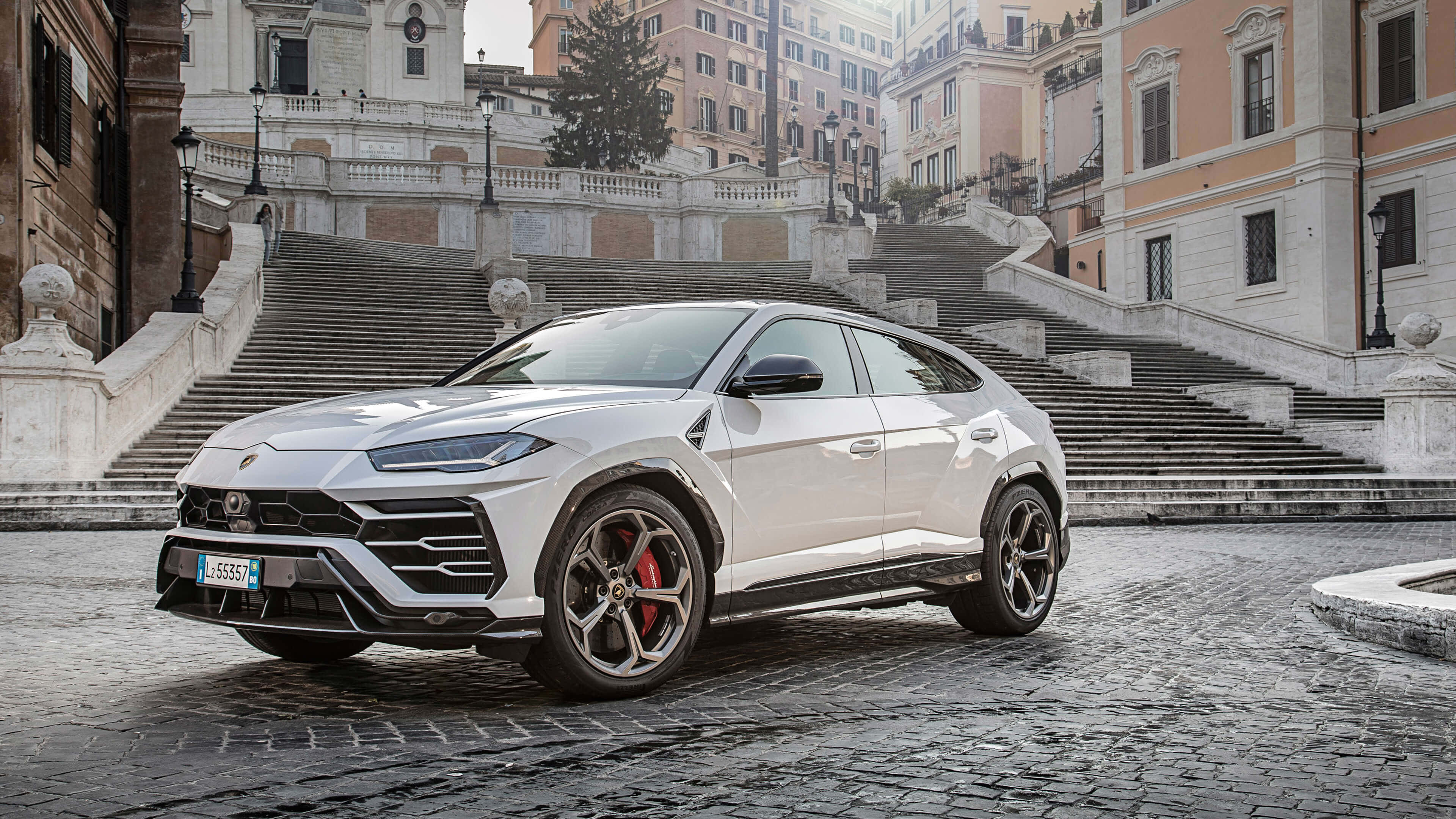 Lamborghini Urus 桌布 壁紙 — 一輛時尚的白色藍寶堅尼Urus SUV停放在歷史悠久的歐洲建築前的鵝卵石台階上。