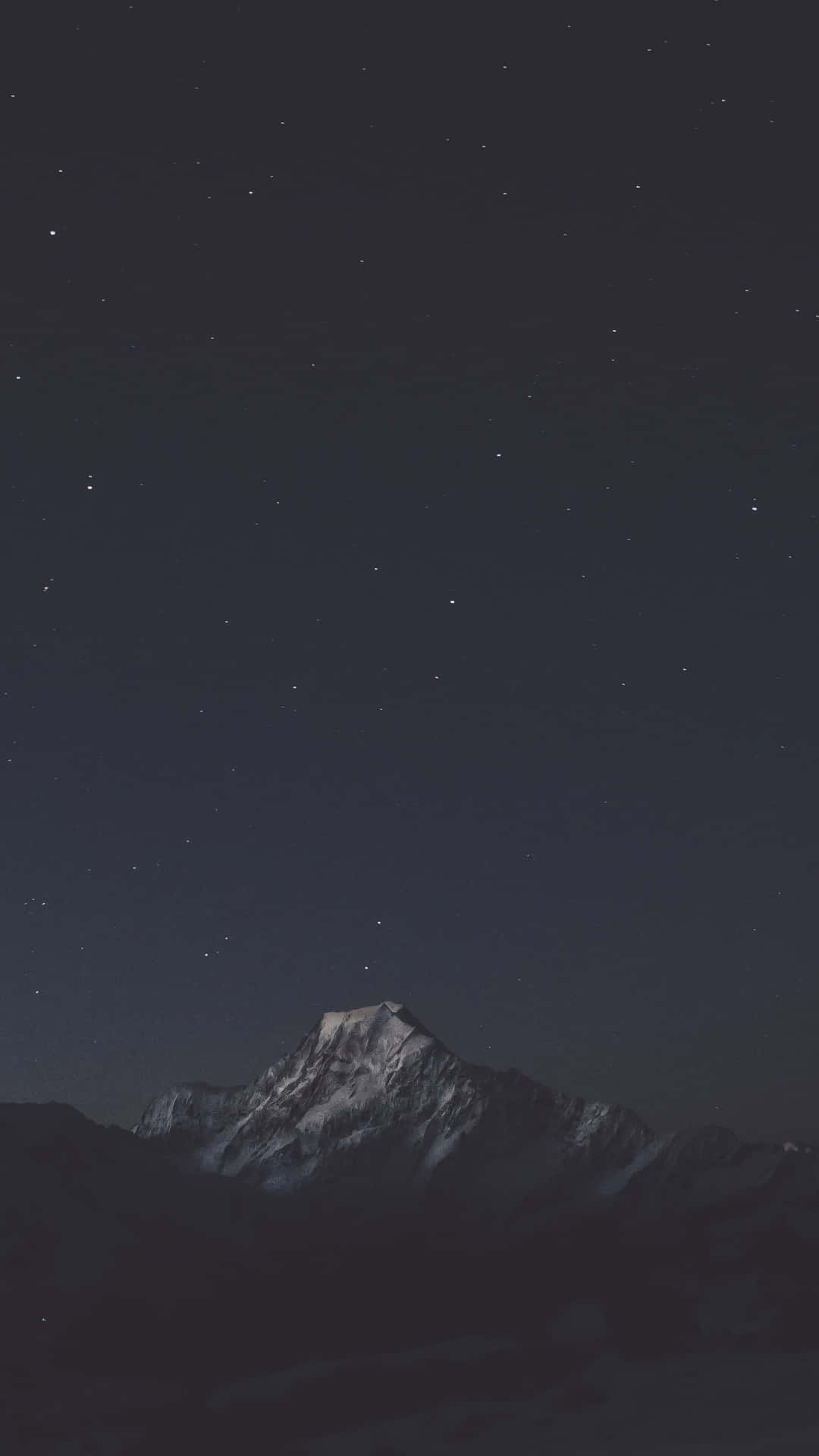  壁紙 — 白雪覆蓋的山峰在繁星點點的夜空下升起，伴隨著微弱的銀河光芒。
