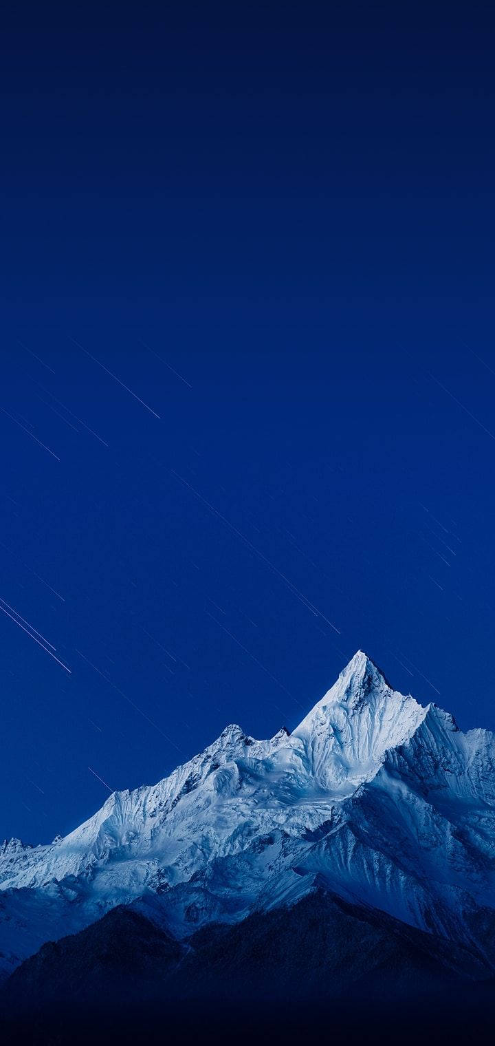 在繁星點點的夜空下，帶有可見星軌的雪覆蓋山頂。 — Realme 壁紙 壁紙