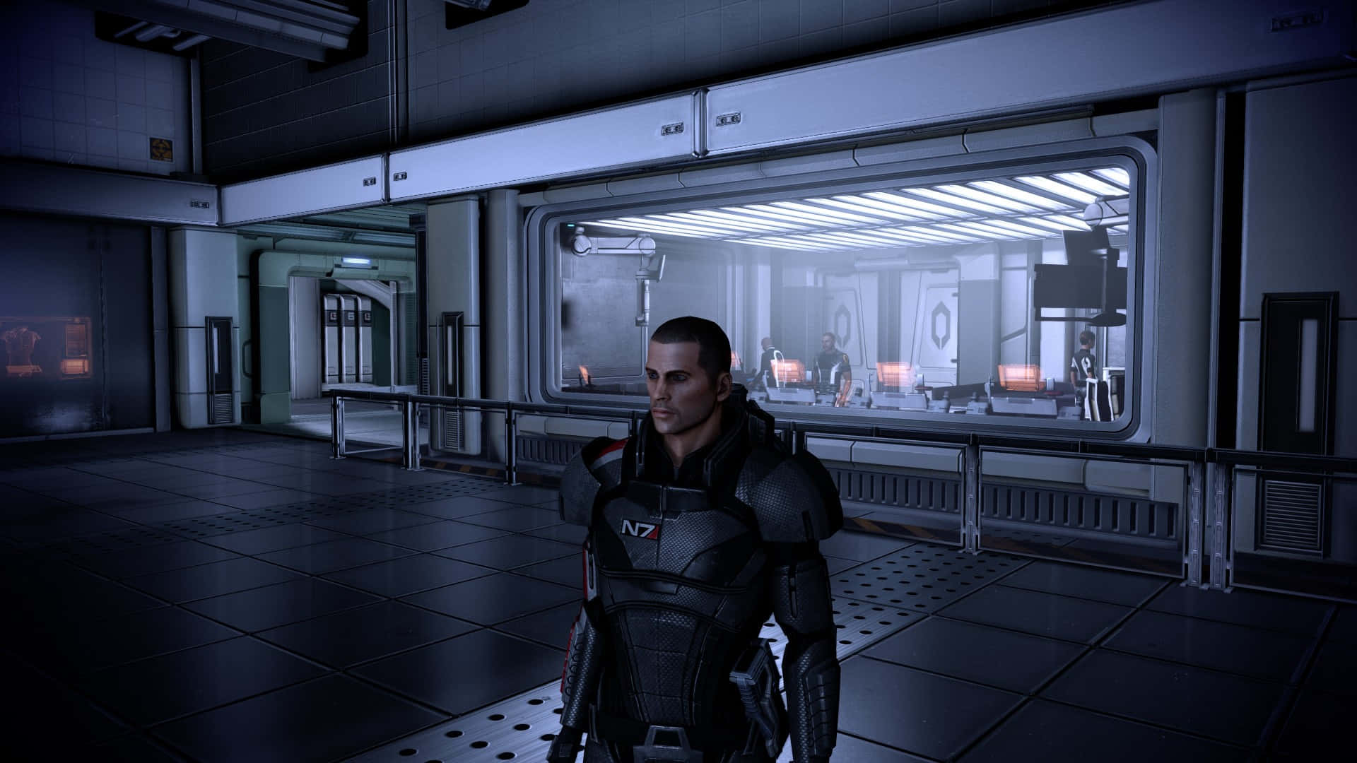 Mass Effect Legendary Edition 桌布 壁紙 — 一名身穿黑色N7裝甲的士兵站在昏暗的未來風格走廊中，身後有發光面板和玻璃牆實驗室。