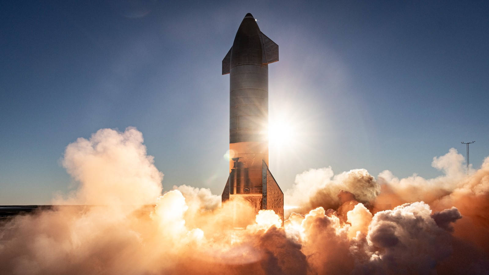 Spacex Starship 桌布 壁紙 — SpaceX Starship 火箭發射到清澈的藍天，下方有熾熱的廢氣和滾滾濃煙。