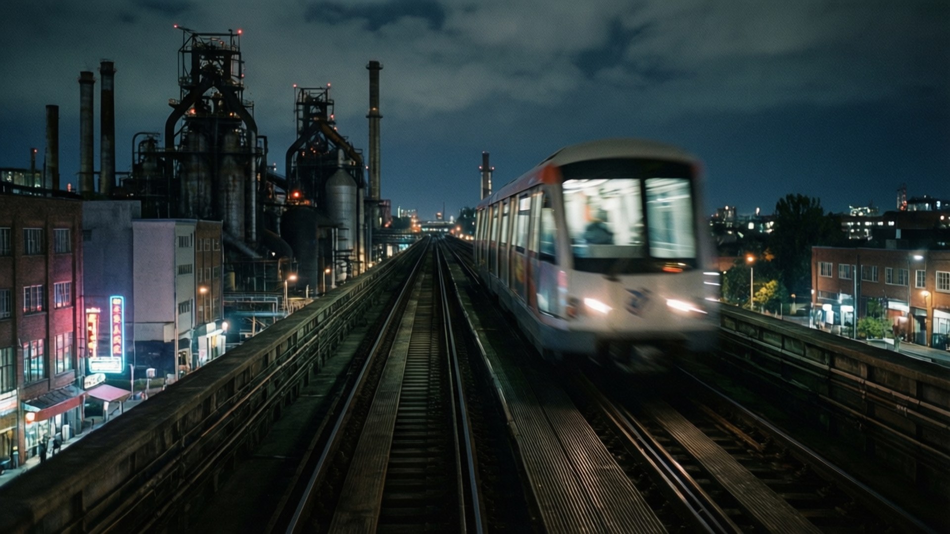 Monorail Night Transit 壁紙 — 一列高速行駛的火車在黑暗的天空下模糊掠過，工業塔樓和發光的城市燈光排列在高架軌道旁。