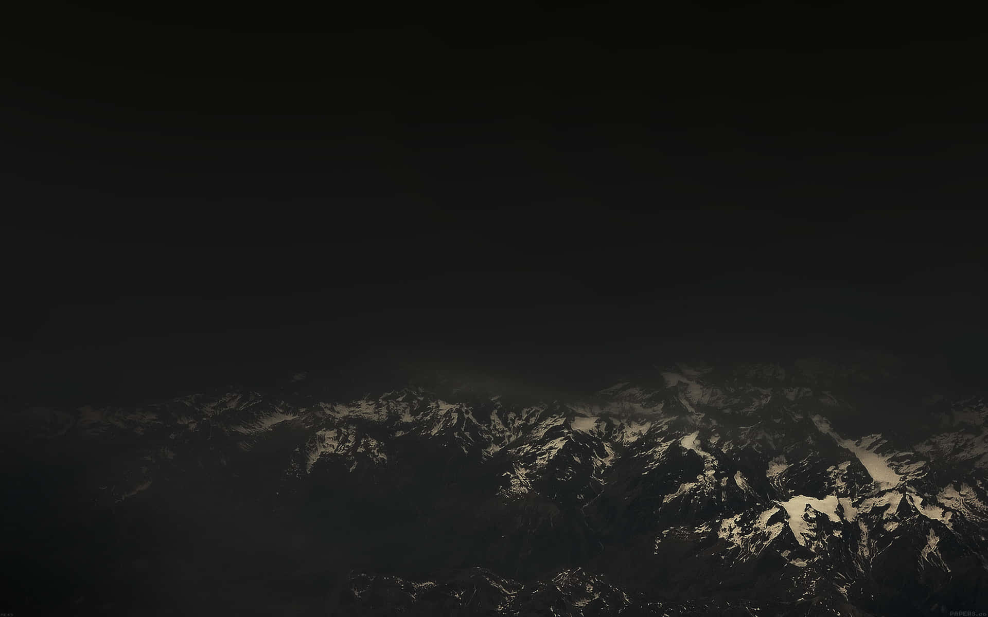  壁紙 — 一座崎嶇的山脈，山頂積雪，在黑暗的天空下從深沉的陰影中浮現。
