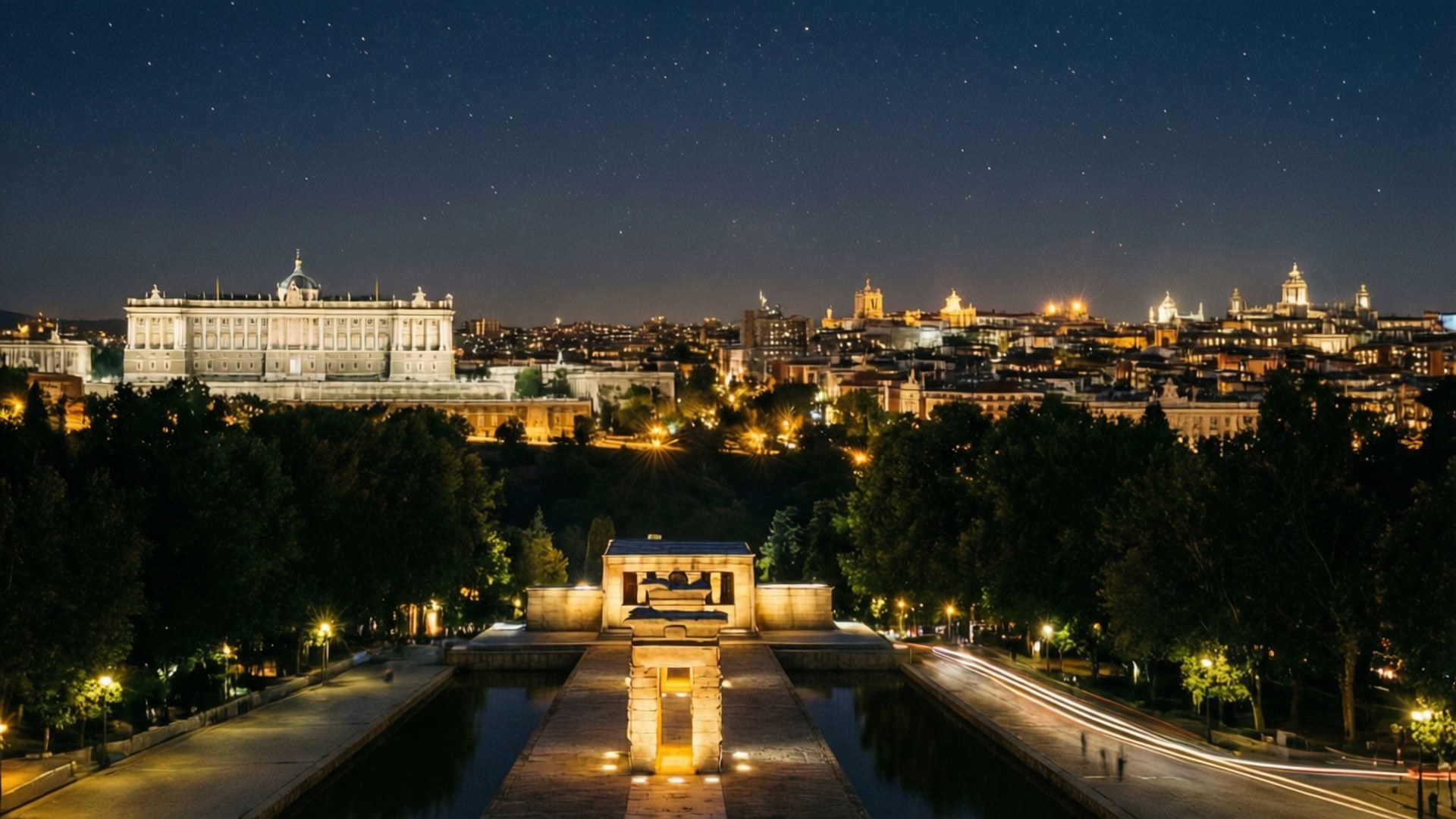 Madrid Skyline Night From Debod 壁紙 — 馬德里皇宮和城市景觀的星空夜景，溫暖的燈光照明，前景有一座亮燈的埃及風格紀念碑。