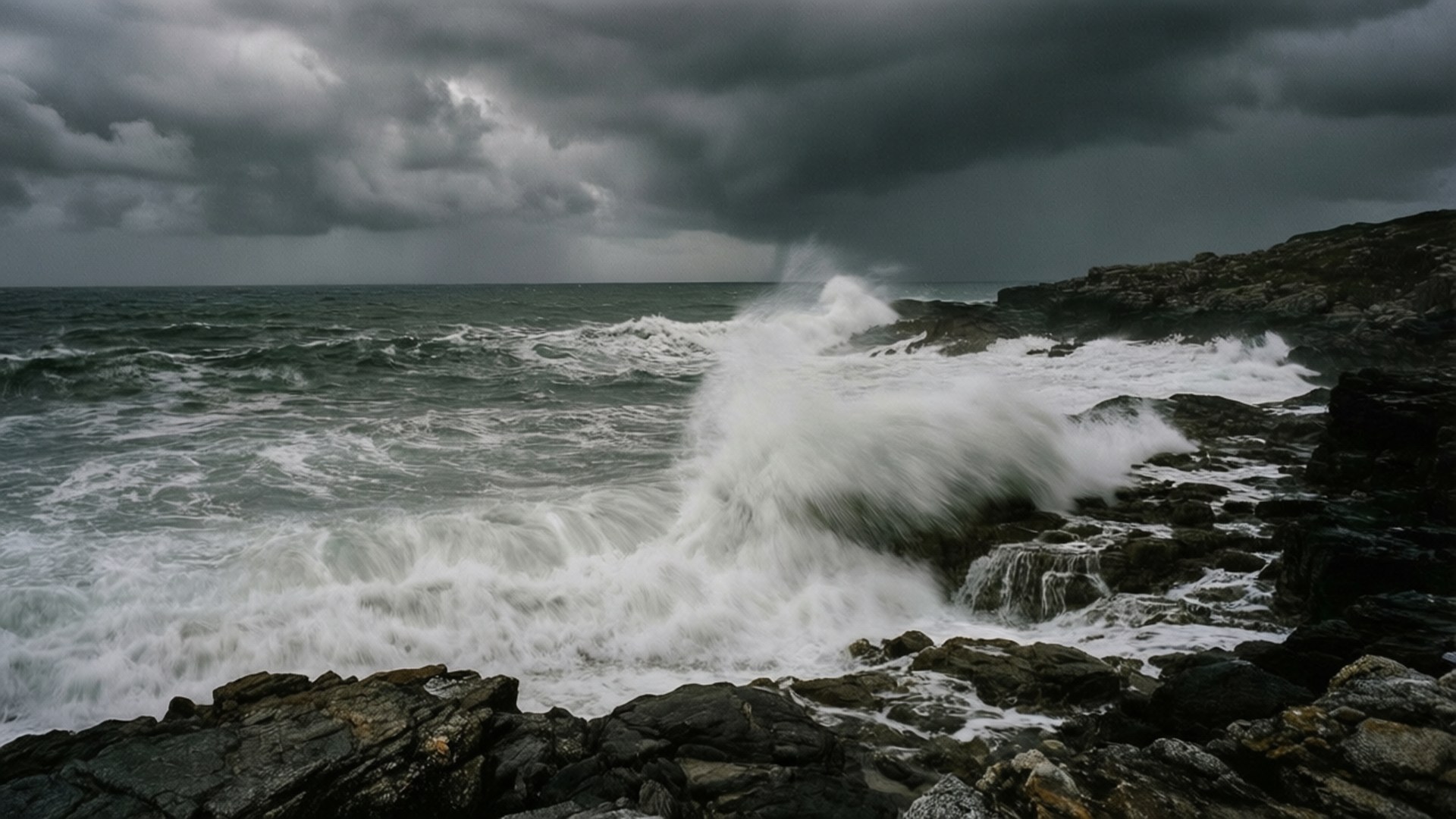 Stormy Grey Seascape 壁紙 — 在沉重的灰色天空下，波濤洶湧的大海撞擊著黑暗的鋸齒狀岩石。