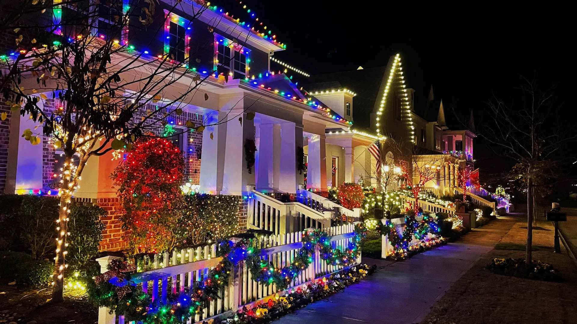  壁紙 — 夜晚的街道閃爍著充滿活力的節日燈飾，點綴著房屋的圍欄和樹木，營造出節日魔幻的氛圍。